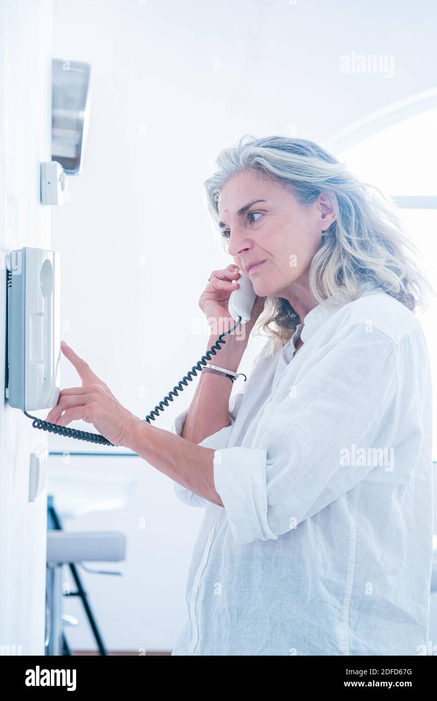 Femme utilisant un interphone (visite à domicile, livraison). Banque D'Images