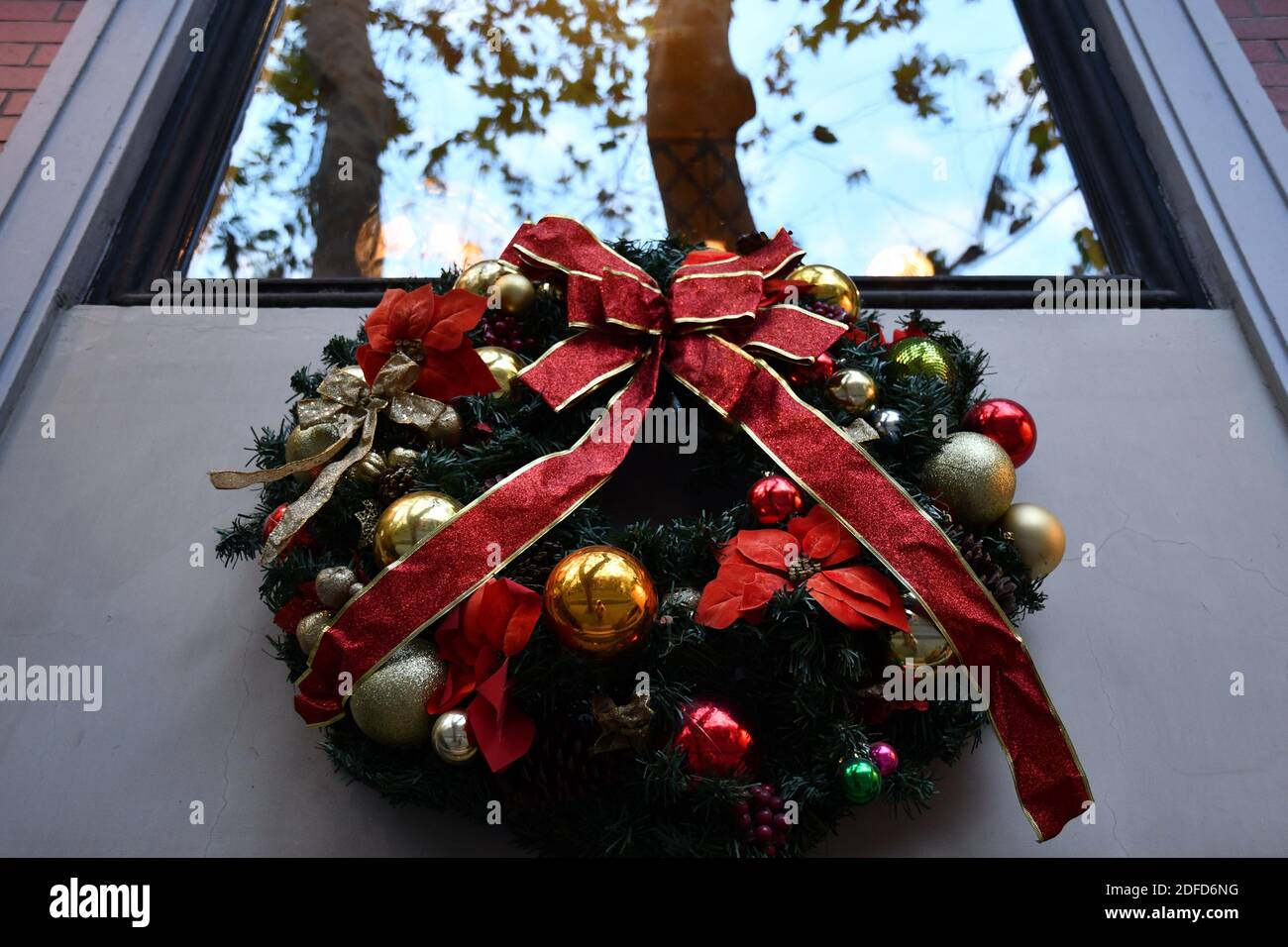 Couronne de Noël rétro en branches de sapin vert et boules dorées avec noeud en ruban rouge. Décoration de bienvenue sous la fenêtre Banque D'Images