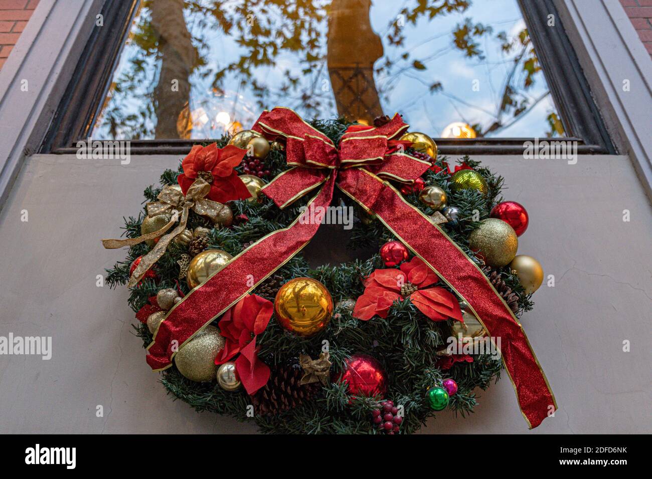 Couronne de Noël traditionnelle faite de branches de sapin vert et de boules dorées avec noeud en ruban rouge. Décoration de bienvenue de vacances Banque D'Images