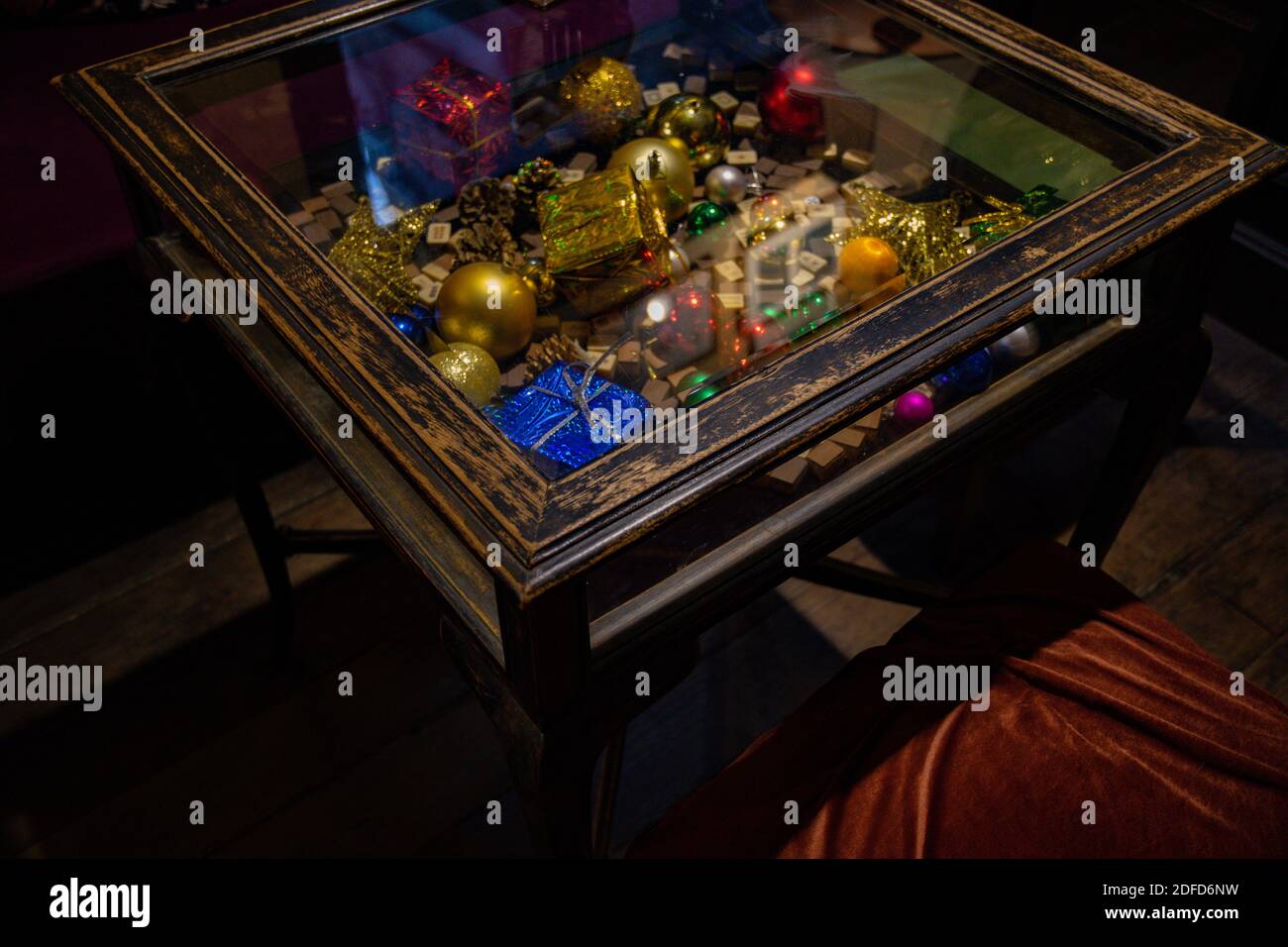 Table en bois vintage avec boules de Noël dorées, cadeaux de Noël bleus emballés et cubes de bois de mahjong sous plan d'examen en verre. Décorations d'intérieur de vacances Banque D'Images