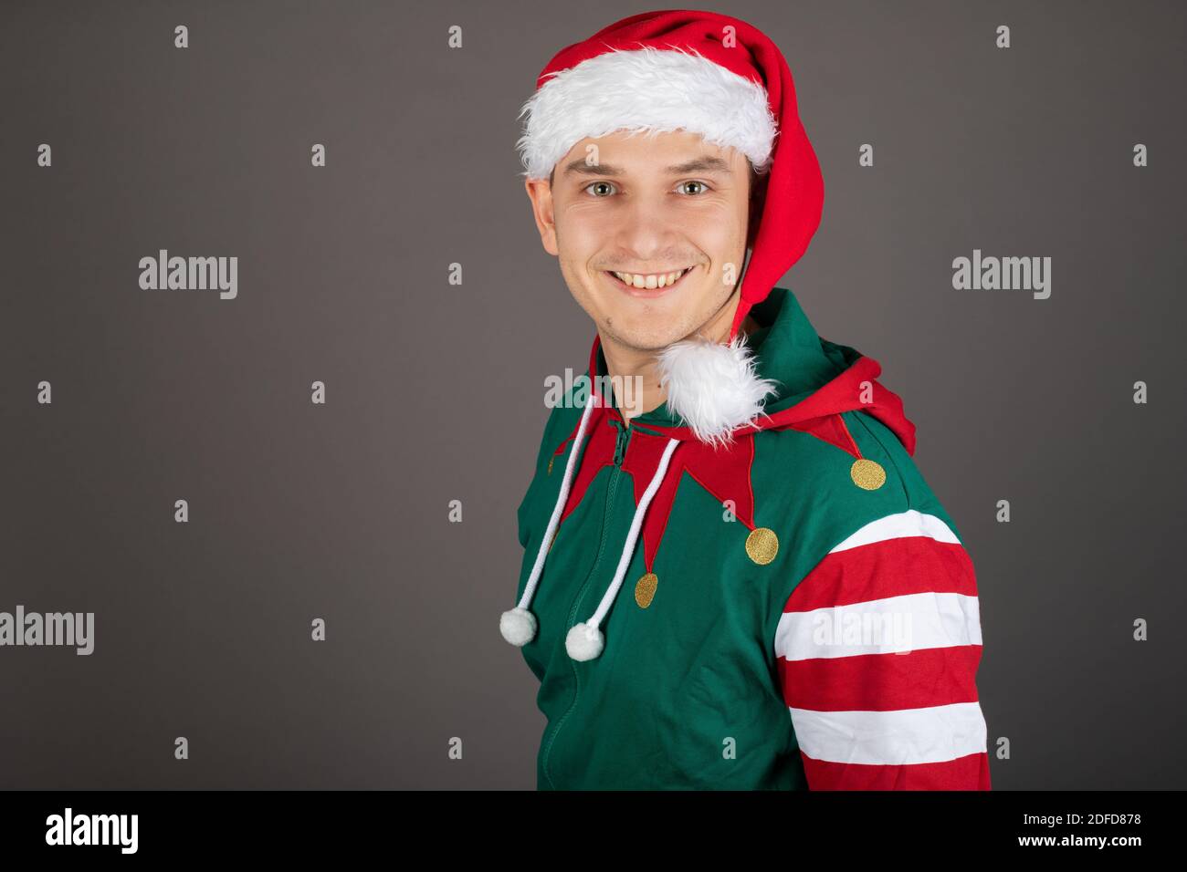 Portrait de l'homme beau portant le costume de Grinch est souriant à l'appareil photo sur fond gris Banque D'Images