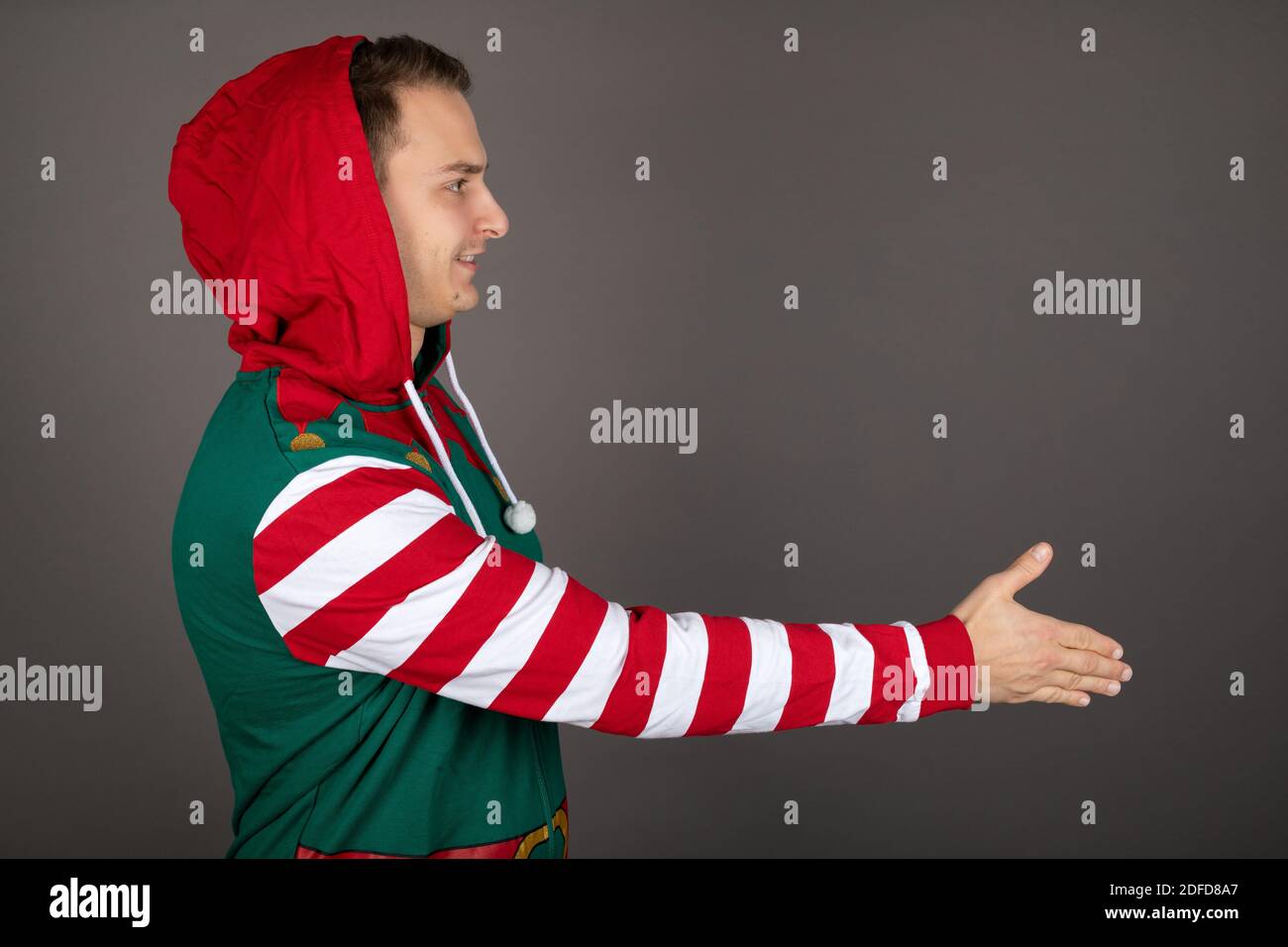 L'homme portant le costume d'orf du Père Noël se secoue les mains sur le gris arrière-plan Banque D'Images