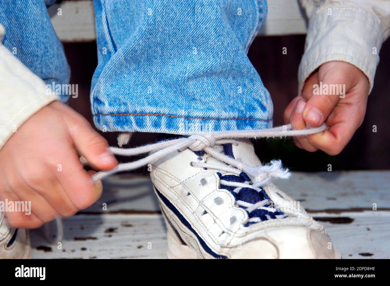 Garçon de quatre ans apprenant à attacher des lacets de chaussures Banque D'Images