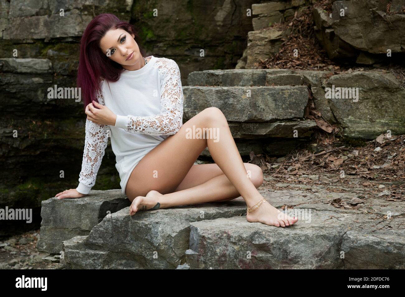 Portrait d'une jeune femme en blanc, en haut, assis et posant sur des roches, Canada Banque D'Images