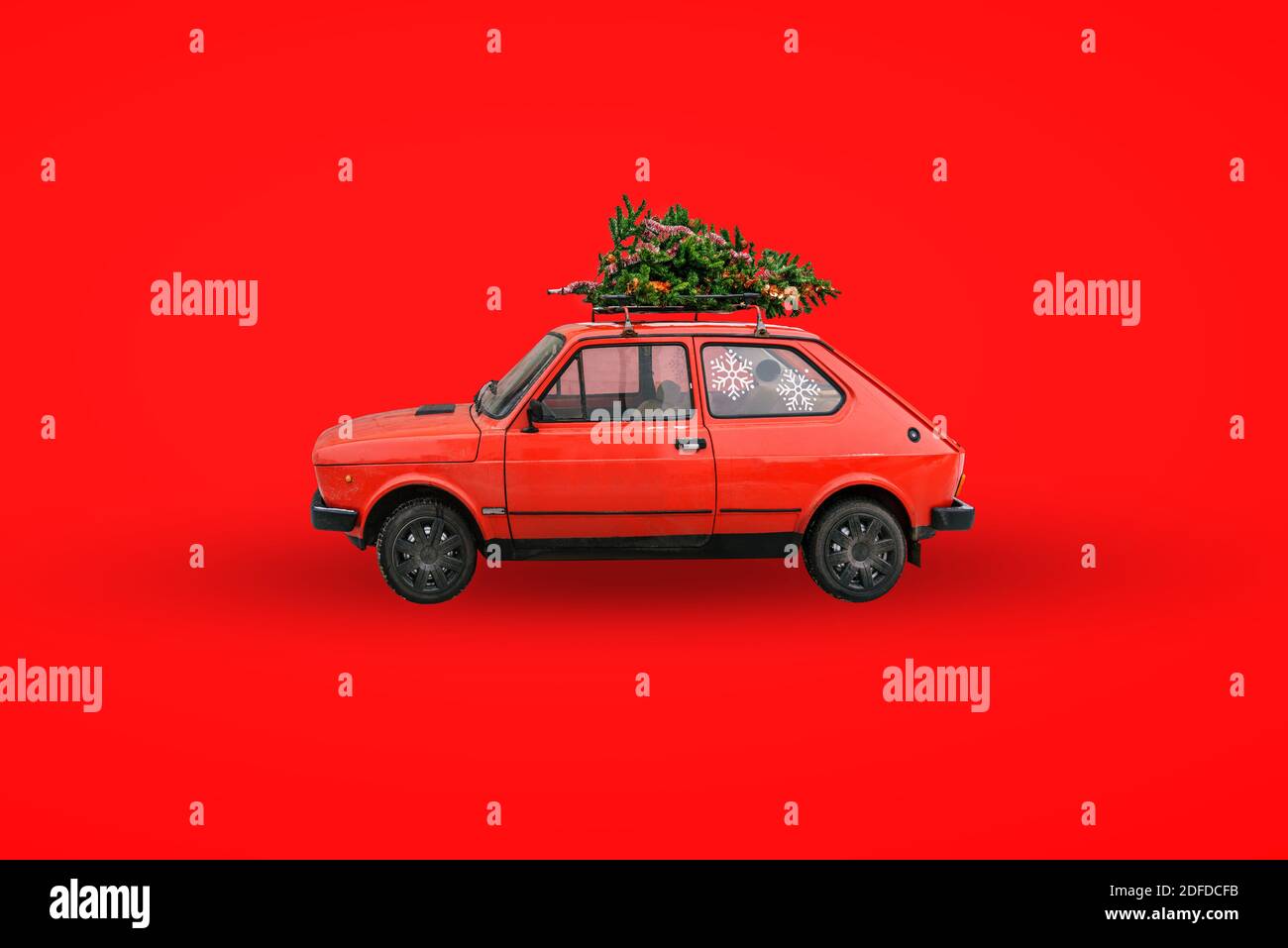 Voiture rétro rouge. Arbre de Noël sur le toit de la voiture. Livraison de marchandises, voyages du nouvel an et visites. Arrière-plan de Noël. Banque D'Images