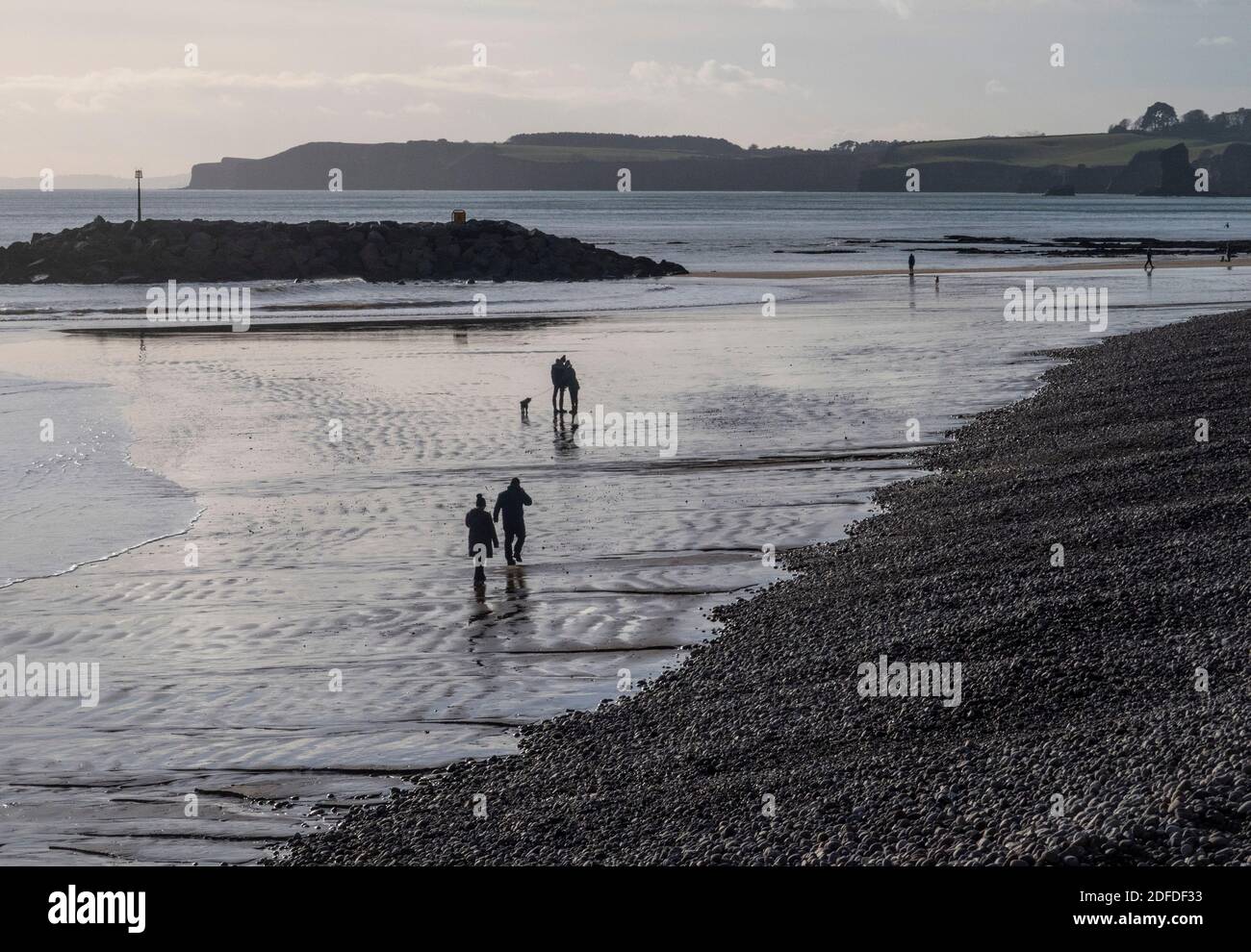 Les gens qui marchent en hiver sur la plage à Sidmouth, Devon, Angleterre, Royaume-Uni par une journée froide mais claire. Banque D'Images Les gens qui marchent en hiver sur la plage à Sidmouth, Devon, Angleterre, Royaume-Uni par une journée froide mais claire. Banque D'Images