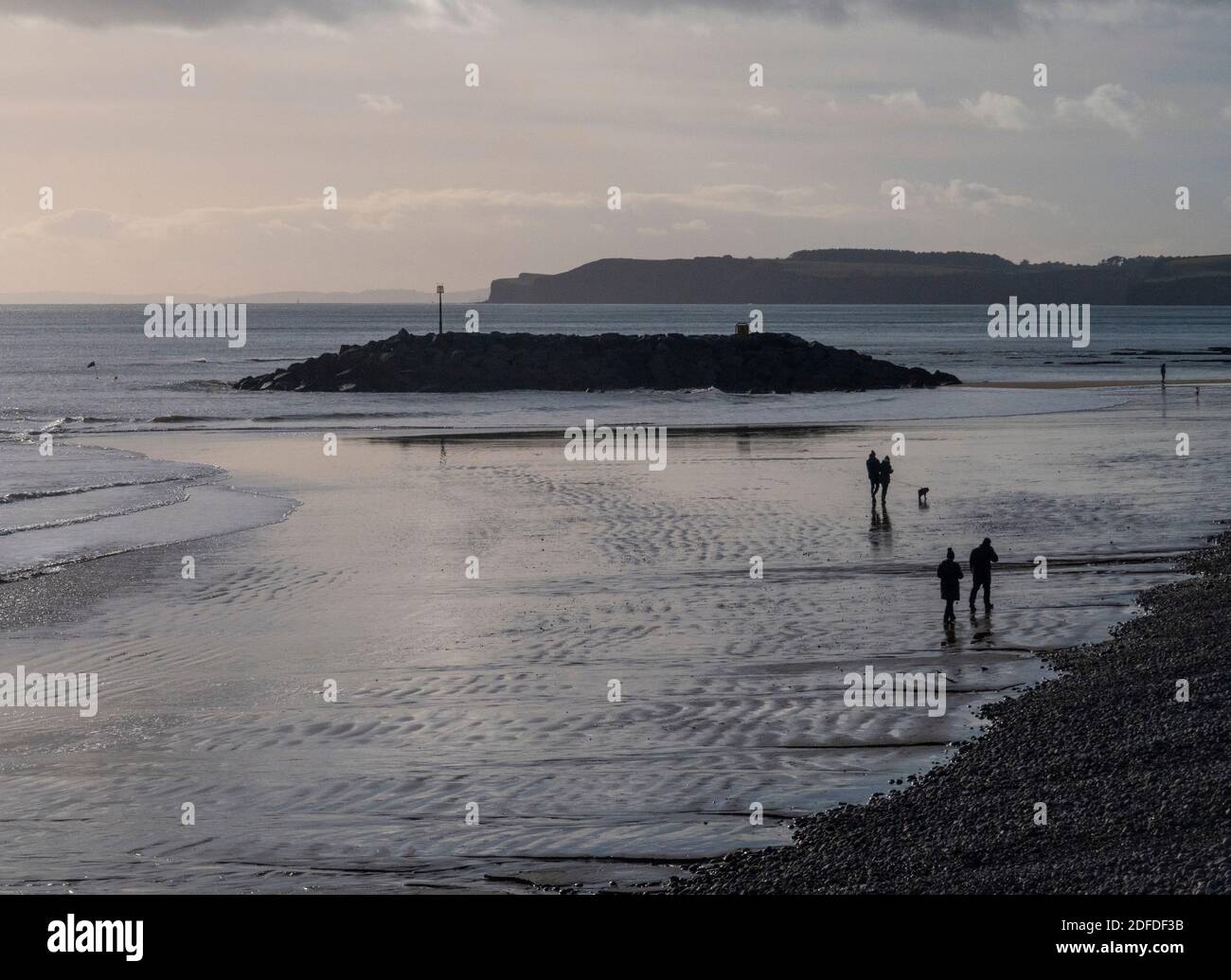 Les gens qui marchent en hiver sur la plage à Sidmouth, Devon, Angleterre, Royaume-Uni par une journée froide mais claire. Banque D'Images Les gens qui marchent en hiver sur la plage à Sidmouth, Devon, Angleterre, Royaume-Uni par une journée froide mais claire. Banque D'Images