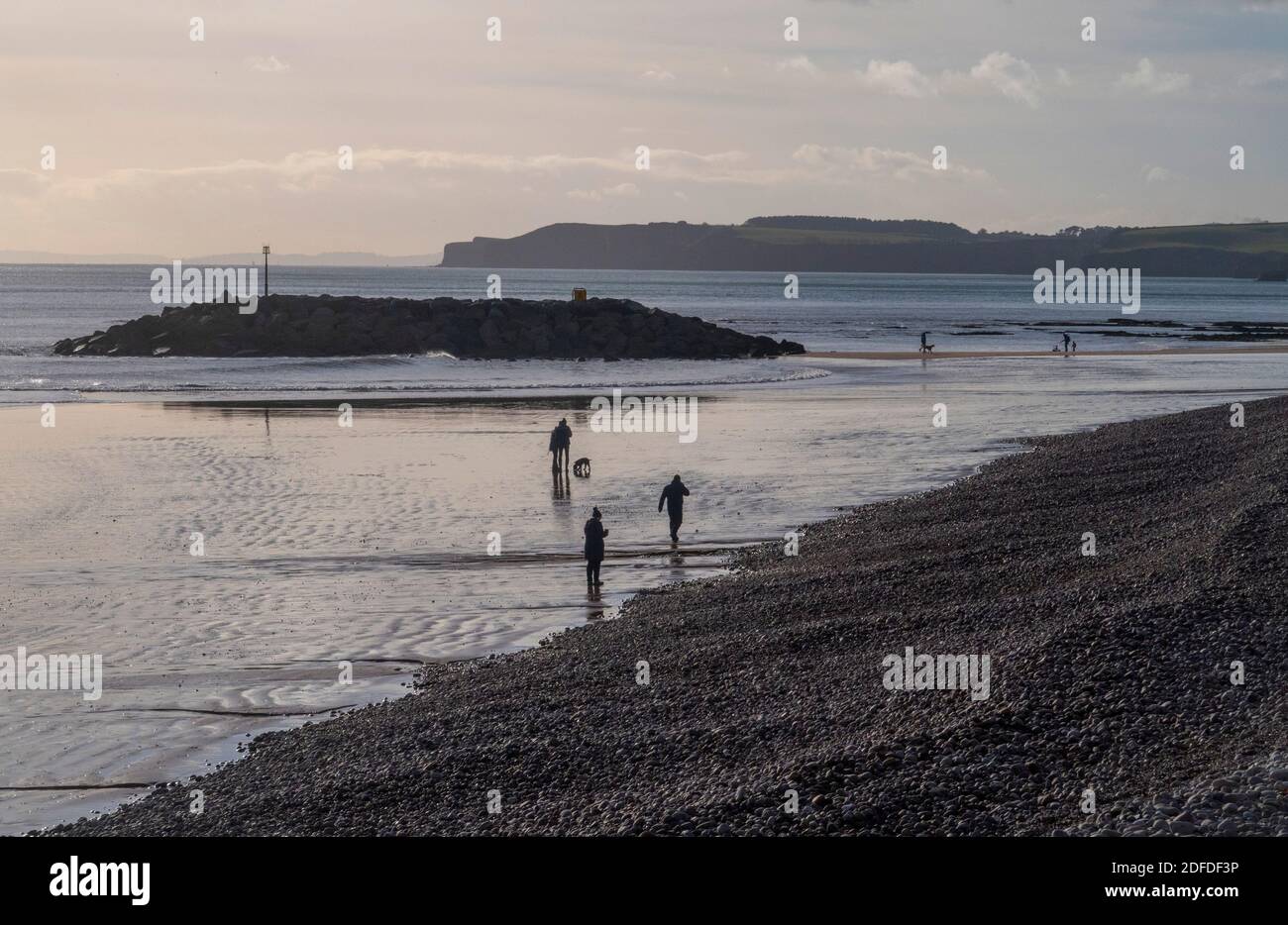 Les gens qui marchent en hiver sur la plage à Sidmouth, Devon, Angleterre, Royaume-Uni par une journée froide mais claire. Banque D'Images Les gens qui marchent en hiver sur la plage à Sidmouth, Devon, Angleterre, Royaume-Uni par une journée froide mais claire. Banque D'Images