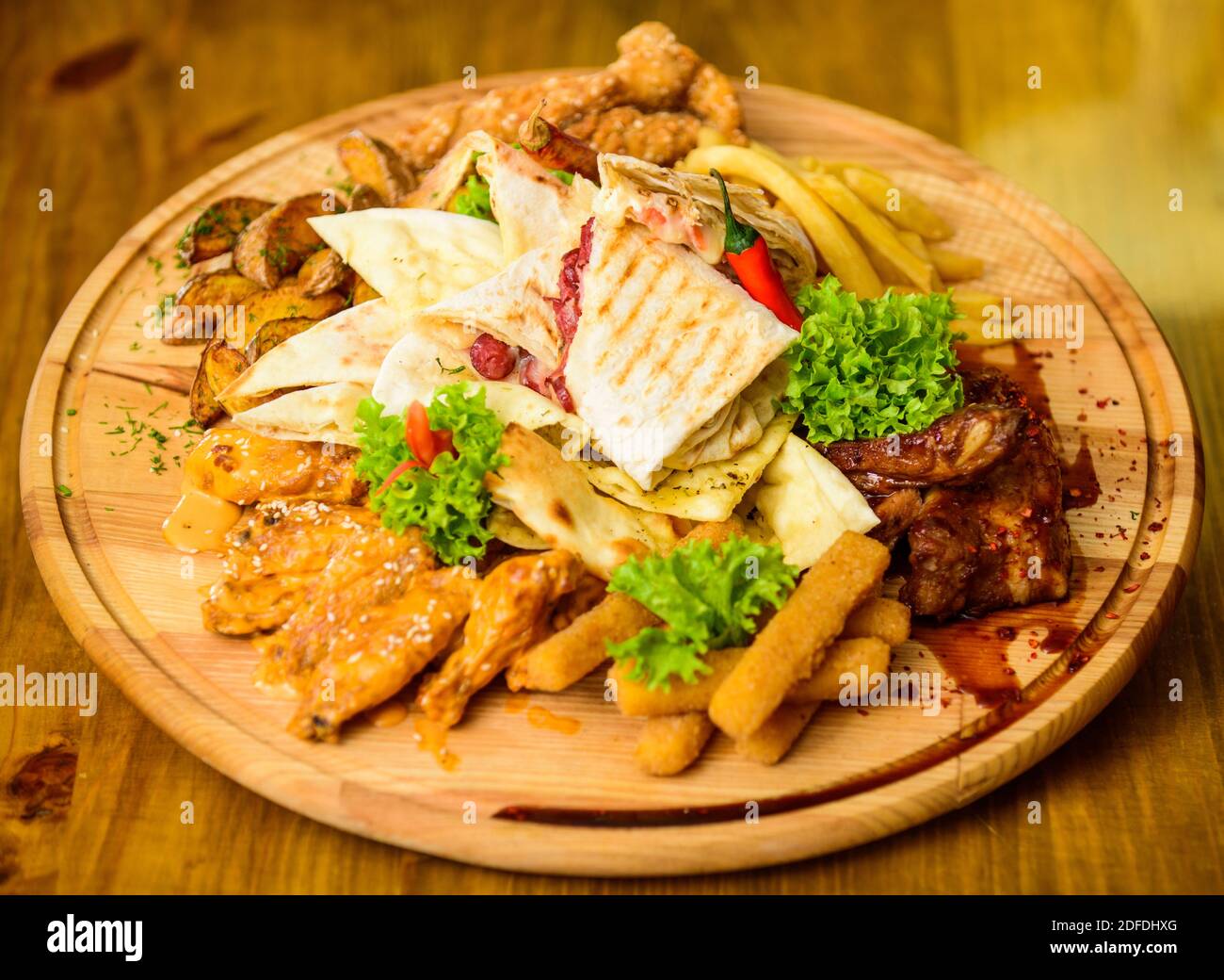 Snack de viande pour le groupe d'amis. De délicieux en-cas savoureux. Les repas au restaurant. Snack pour la bière. Planche de bois frites et bâtonnets de poisson viande burrito steak servi avec une salade. Profitez de votre repas. Menu snack-bar. Banque D'Images