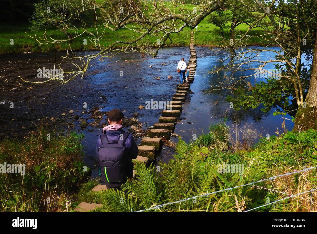 Une famille traversant la rivière Hodder en utilisant les pierres de pas à Whitewell, Lancashire, en 2020. Banque D'Images