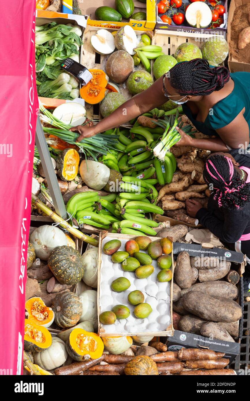 Vue d'en haut d'une femme qui fait du shopping pour des légumes dans une rue à Brixton Market, Electric Avenue, Brixton, Londres Banque D'Images