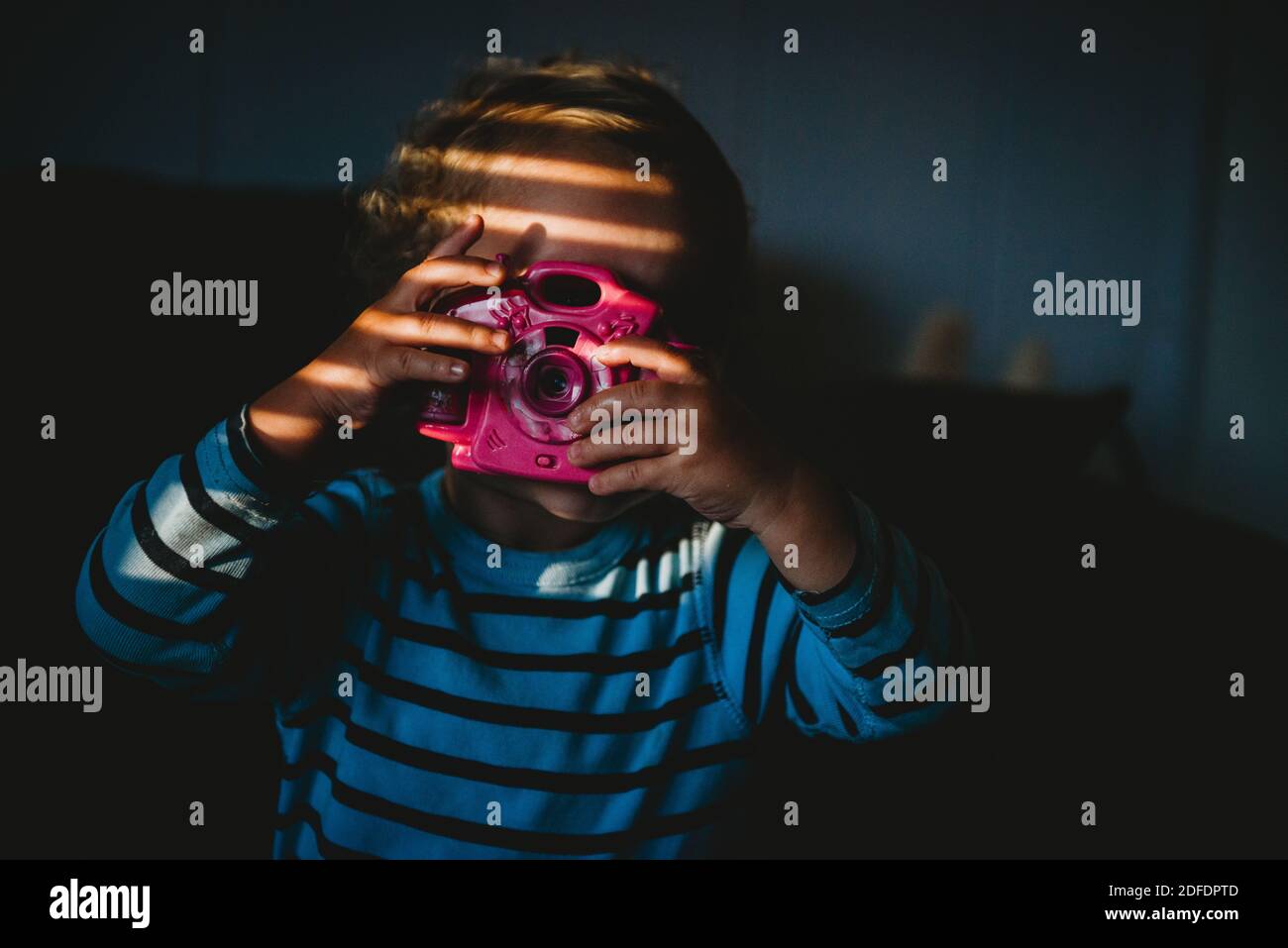 Jeune enfant prétendant prendre une photo avec un appareil photo jouet intérieur à la maison Banque D'Images