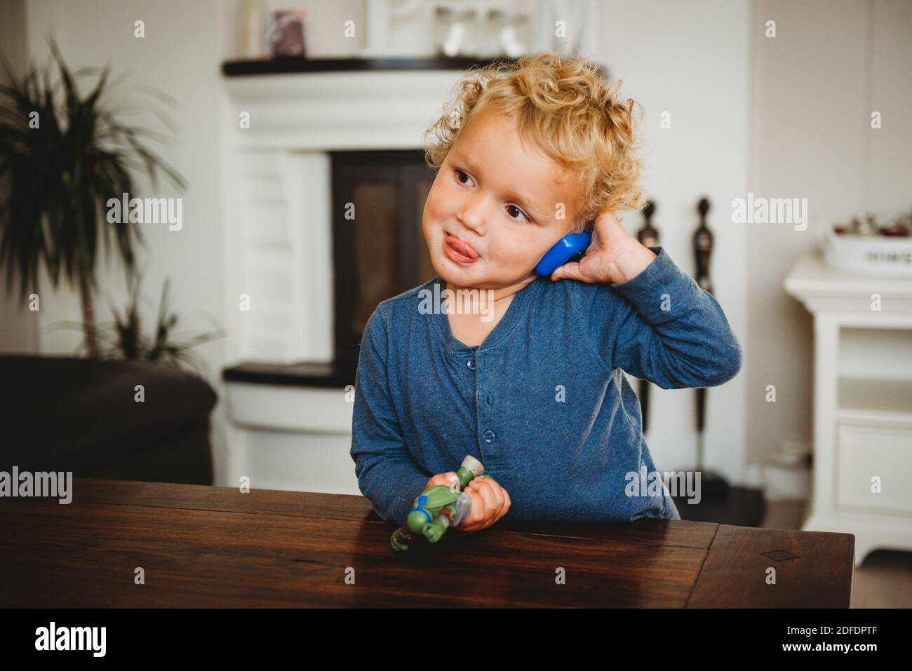 Adorable garçon blond faisant semblant de parler sur le téléphone jouet avec timon vers l'extérieur Banque D'Images