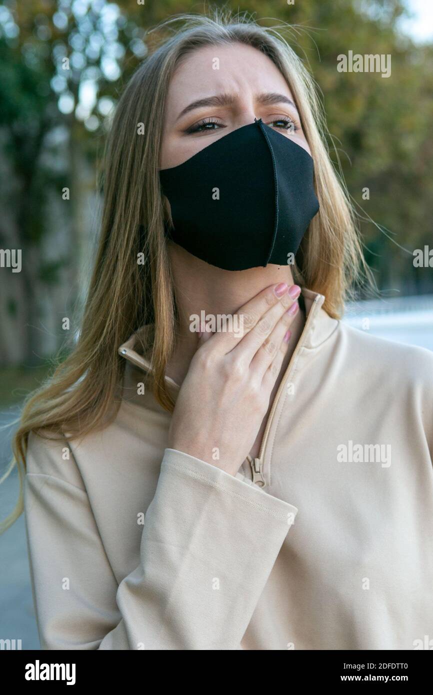 Femme avec un masque de protection ayant un mal de gorge Photo Stock - Alamy