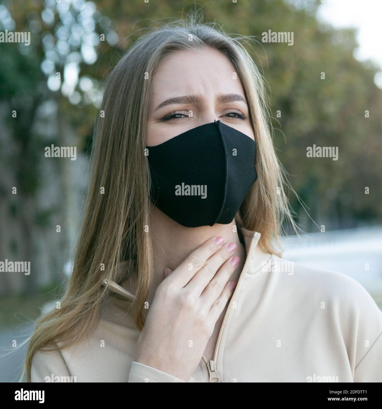 Femme avec un masque de protection ayant un mal de gorge Banque D'Images