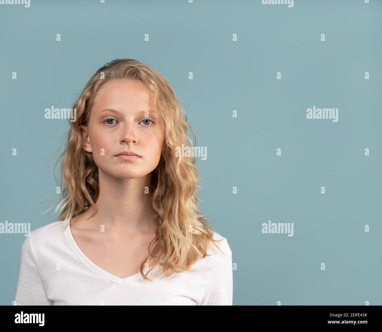 Belle jeune femme blonde sérieuse intelligente sans maquillage sur la couleur tonalité neutre Banque D'Images