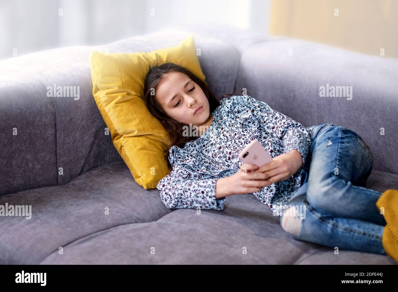 Une adolescente heureuse consulte les réseaux sociaux tout en tenant un smartphone entre ses mains. Une jeune écolière utilise une application de téléphone mobile pour jouer à des jeux, correspon Banque D'Images