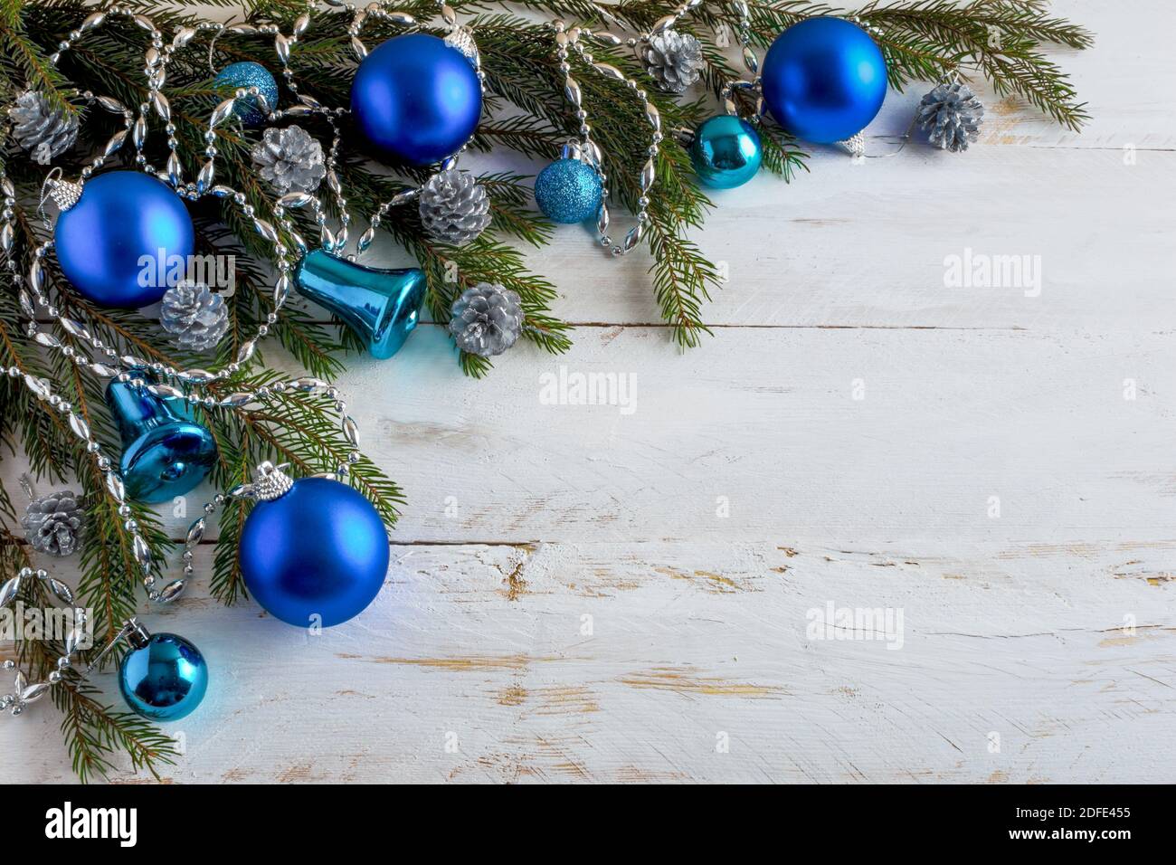 Décoration de Noël boules bleues, branches de sapin, de l'argent des pommes de pins, des cloches sur un fond en bois blanc, copy space Banque D'Images