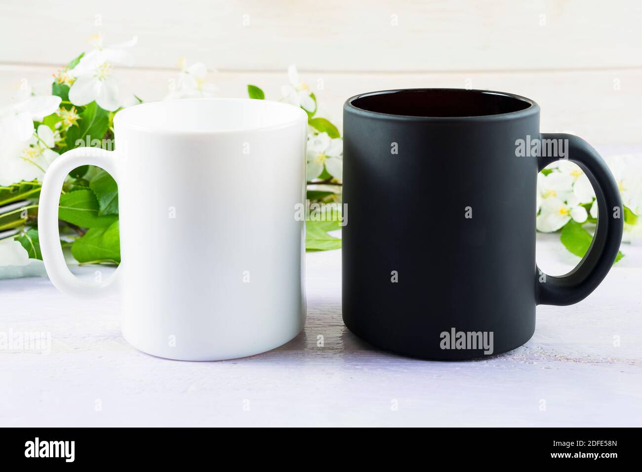 Tasse blanche et noire avec fleur de pomme printanière. Maquette de tasse à café. Vider la maquette de tasse pour la présentation des produits. Banque D'Images