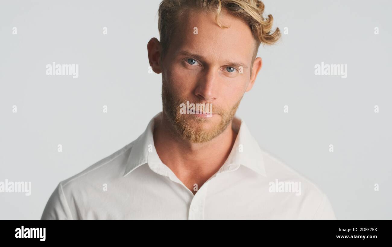 Jeune homme d'affaires beau barbu en chemise regardant avec assurance dans l'appareil photo isolé sur fond blanc Banque D'Images