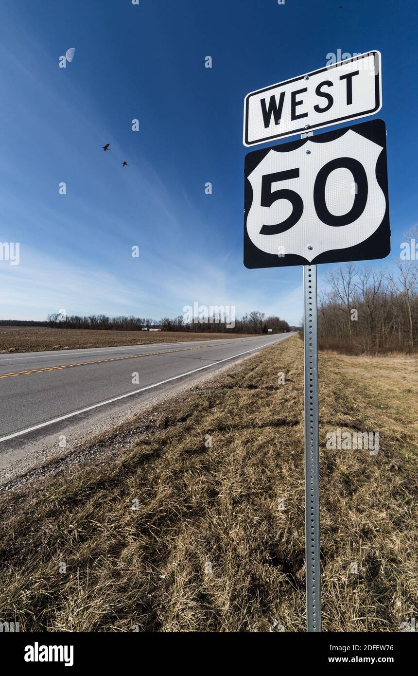 Un marqueur routier sur le côté de l'US-50, à l'extérieur de Brownstown, DANS. Un premier quart de lune et des grues de sable volantes sont en arrière-plan. Banque D'Images