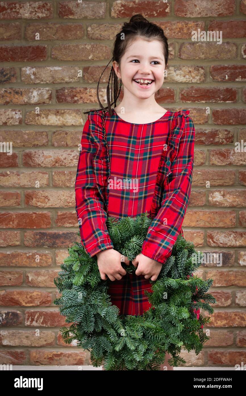 Petite fille en tartan rouge tenue de Noël main verte couronne Banque D'Images