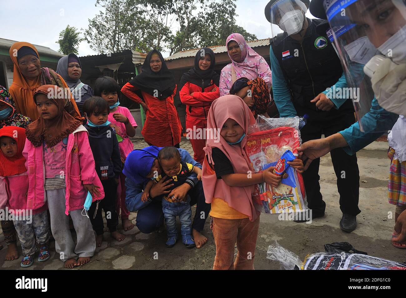 Une femme volontaire vue a donné des points d'esprit pour les enfants qui ont touché par l'éruption du volcan Sinabung pendant a reçu l'aide des volontaires de la Fondation Al Kahfi comme une action d'aide caritative pour les résidents des villages de Kuta Tengah, Berastepu et Gamber (Tiga Serangkai) À la mosquée Al-Jihad à Karo, dans le nord de Sumatra, en Indonésie, le 30 août 2020. Dans plusieurs nouvelles liées à l'éruption du volcan Sinabung, humanely quelques volontaires d'Al-Kahfi sont venus à la psychologie traitée des résidents, en particulier pour les enfants qui vivent sur le seuil d'une zone de danger de catastrophe géologique. Photo par Banque D'Images