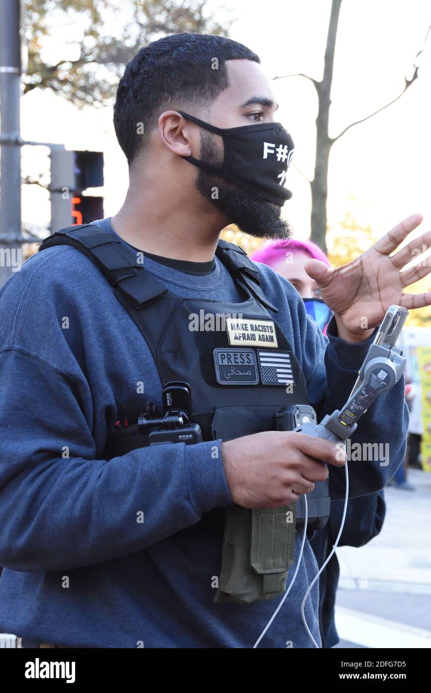 Washington DC. 14 novembre 2020. La marche de Mages. Un homme noir BLM portant un gilet à l'épreuve des balles avec un masque explicite, tenant le téléphone pour l'entrevue. Banque D'Images
