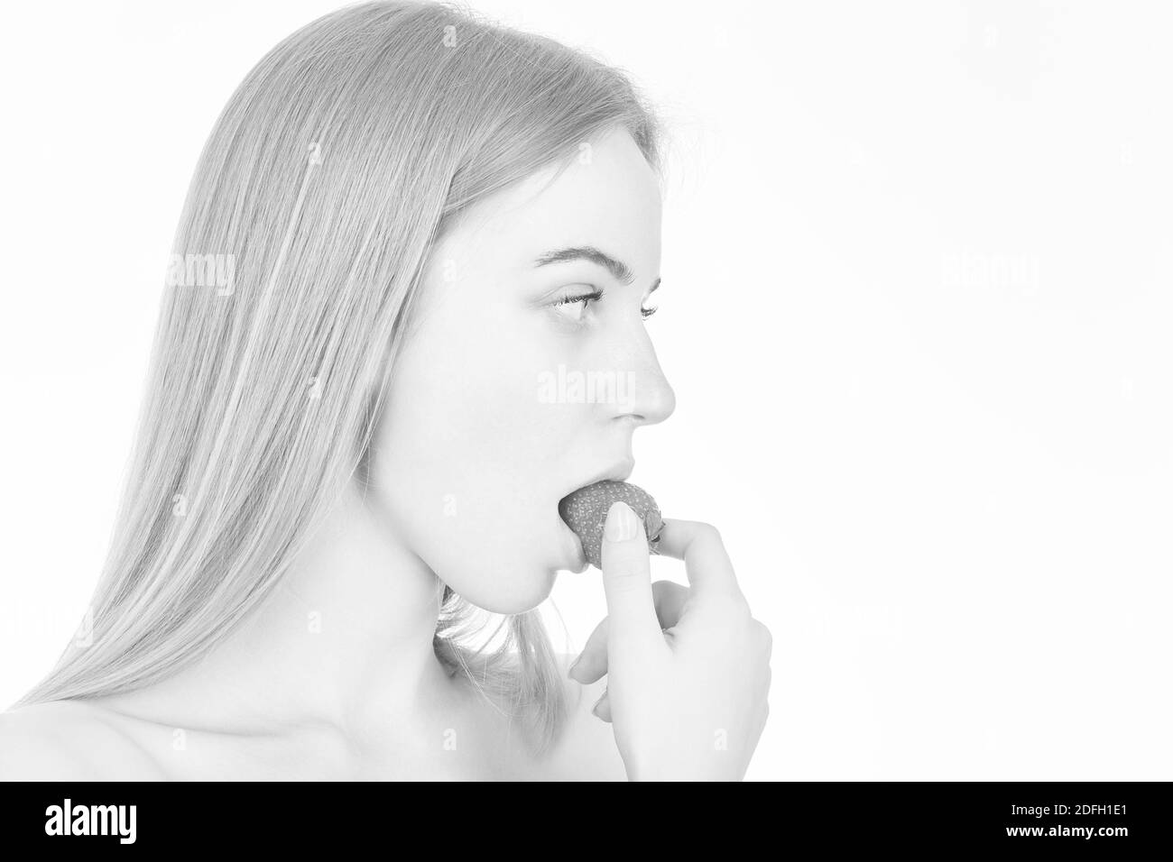 la jeune femme mange de la fraise sur fond blanc avec espace de copie, image monochrome Banque D'Images