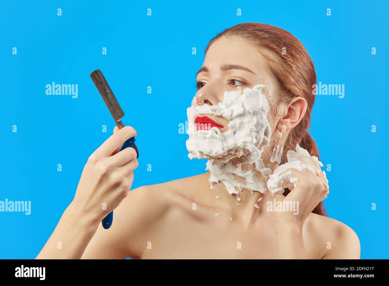 une jeune femme amusante a raser son visage avec un rasoir ouvert sur fond  bleu Photo Stock - Alamy
