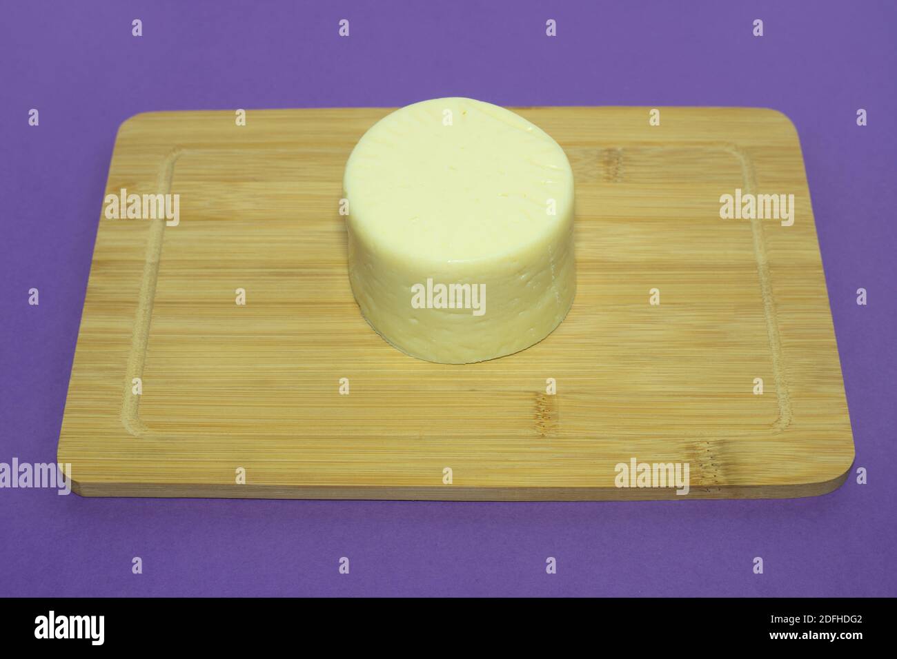 Tête de fromage sur une planche à découper en bois. Une tête de fromage jaune frais sur fond de phylet. Produits laitiers frais pour la cuisine. Banque D'Images