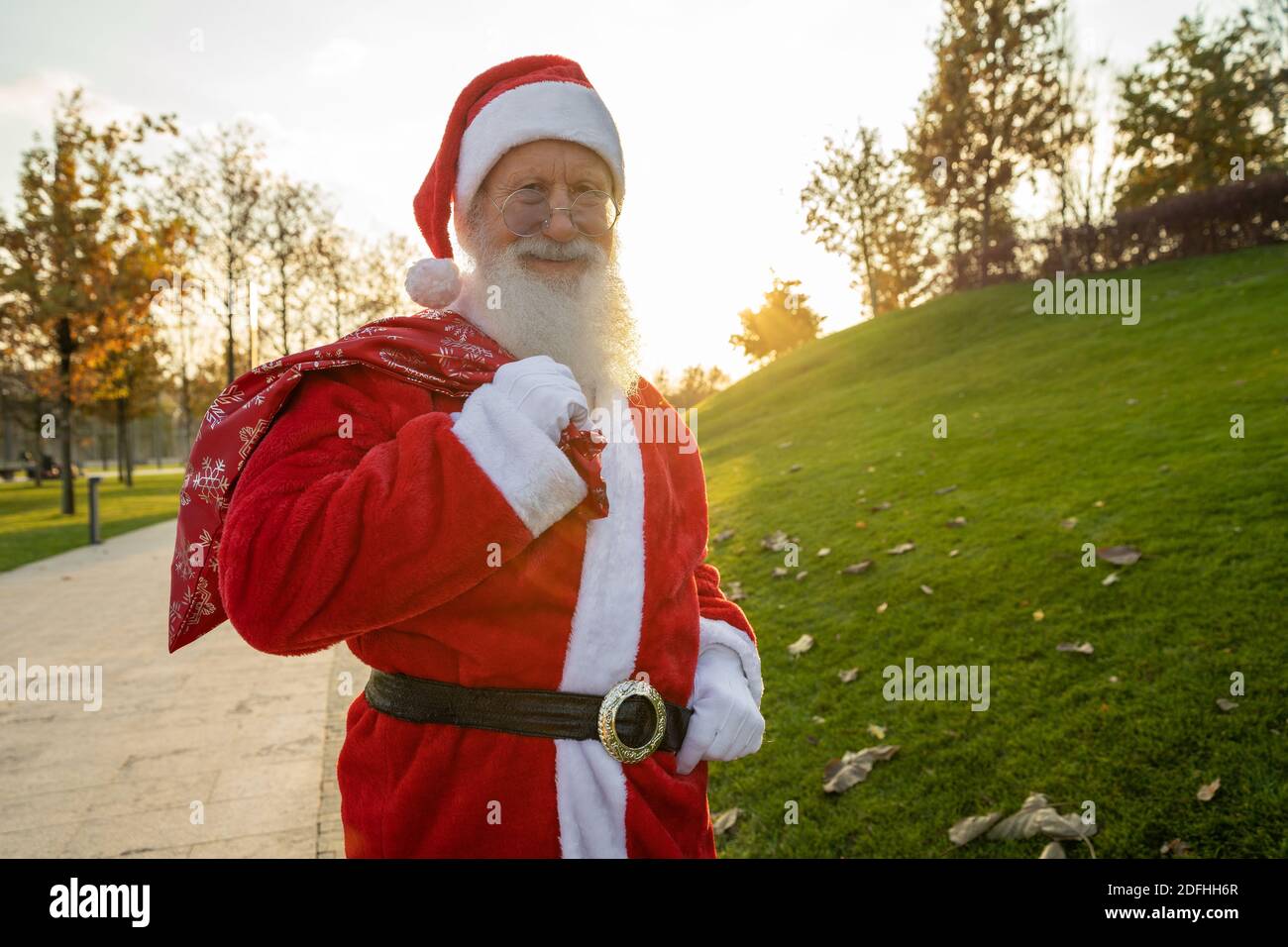Le portrait en gros plan de l'homme heureux senior en costume du père noël revient à l'appareil photo et sourit. L'humeur du nouvel an. Banque D'Images