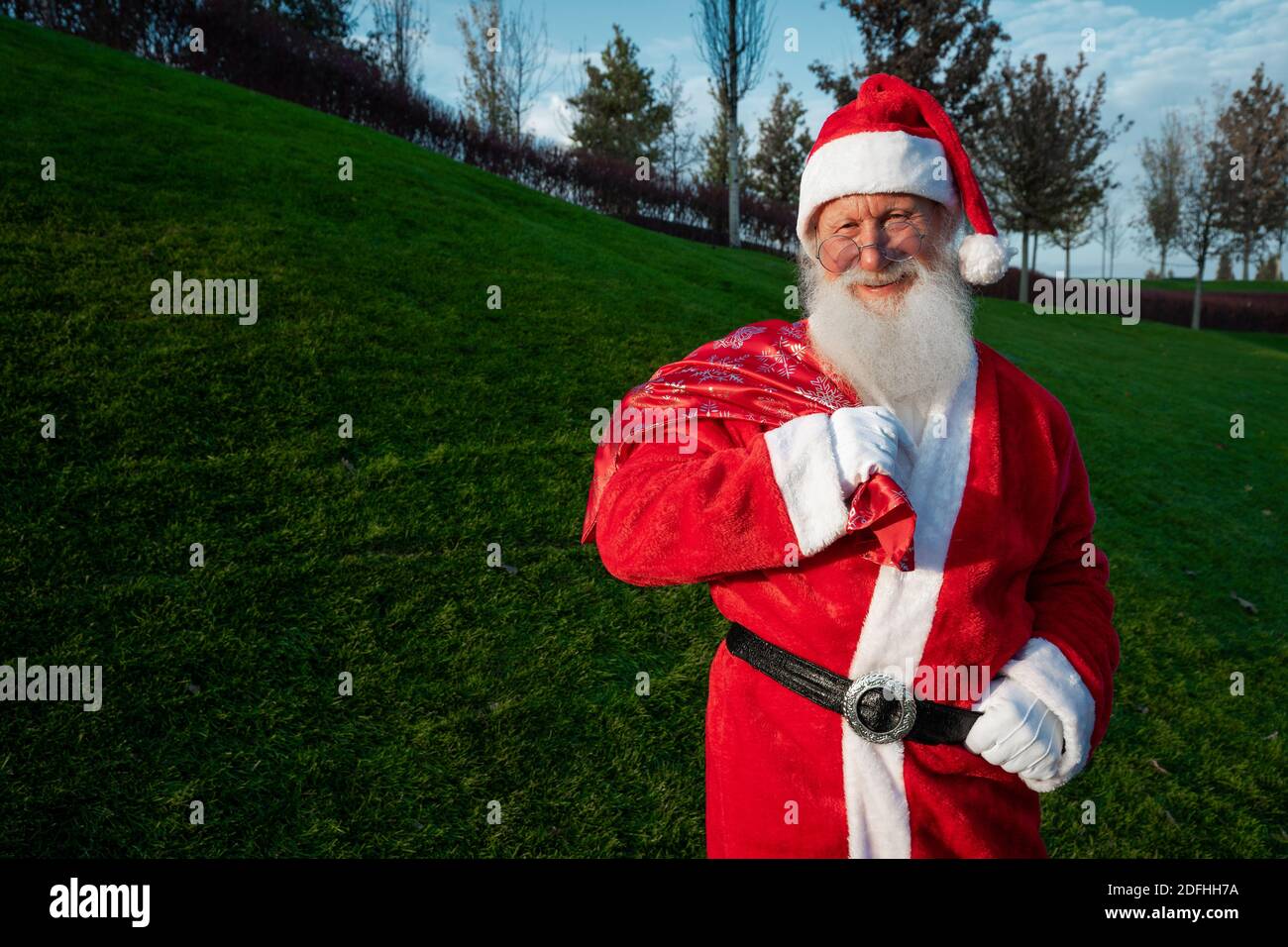 Le portrait en gros plan de l'homme heureux senior en costume du père noël revient à l'appareil photo et sourit. L'humeur du nouvel an. Banque D'Images