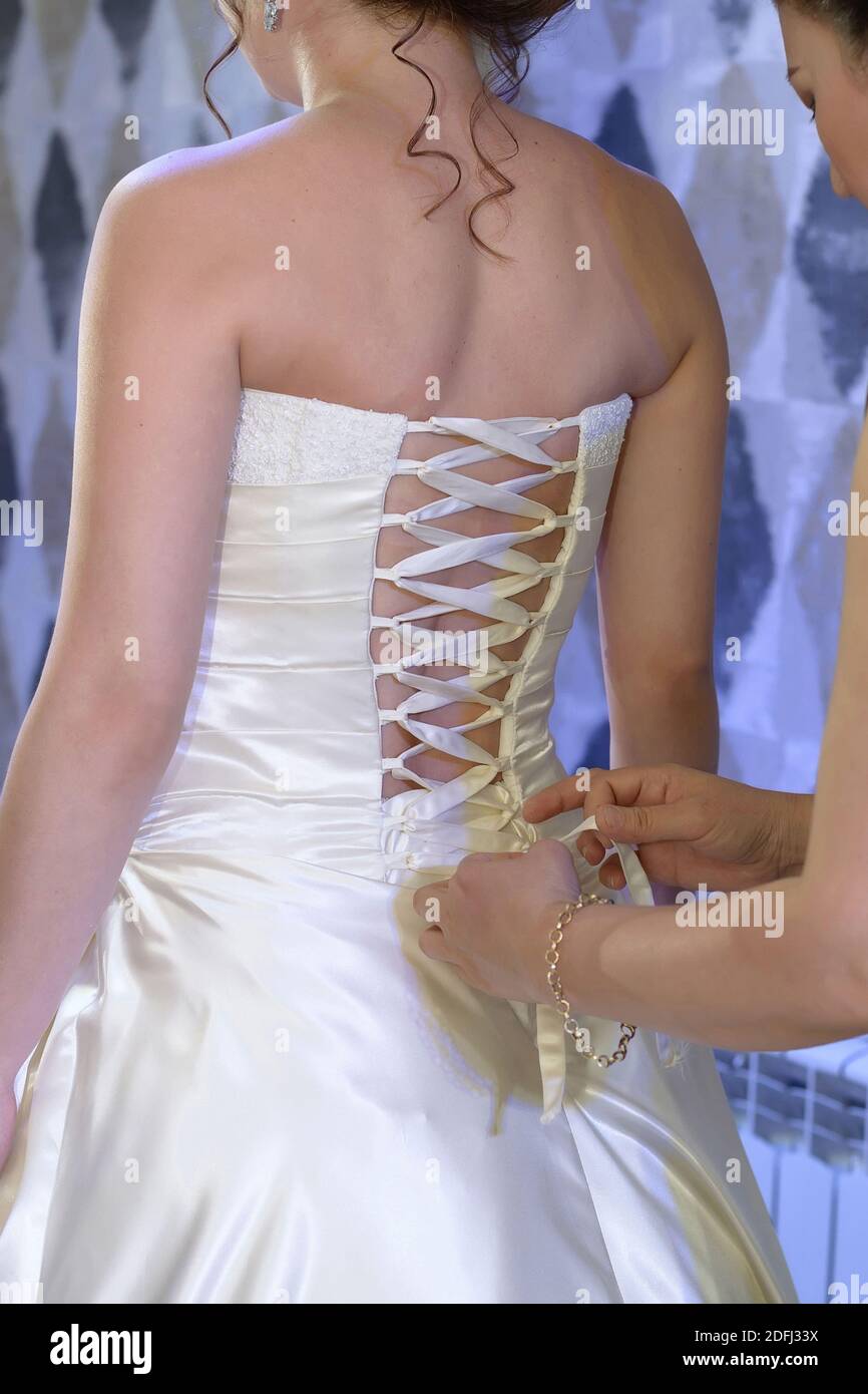 Un ami aide la mariée à lacer le corset sur la robe de mariage. Gros plan,  vue arrière Photo Stock - Alamy
