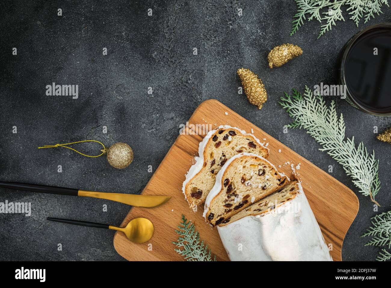 Composition de Noël avec gâteau au stollen sur une planche à bois, tasse à café et couverts sur fond sombre. Flat lay, vue de dessus Banque D'Images