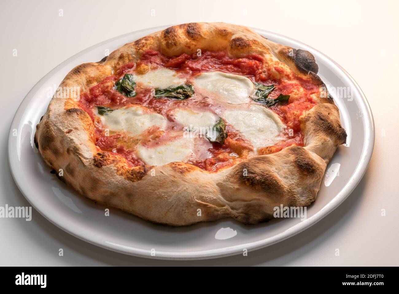 Pizza de Naples, Italie, appelée margherita parce qu'il est dédié à la reine - pizza avec bord croustillant, tomate, mozzarella et basilic dans la plaque blanche Banque D'Images