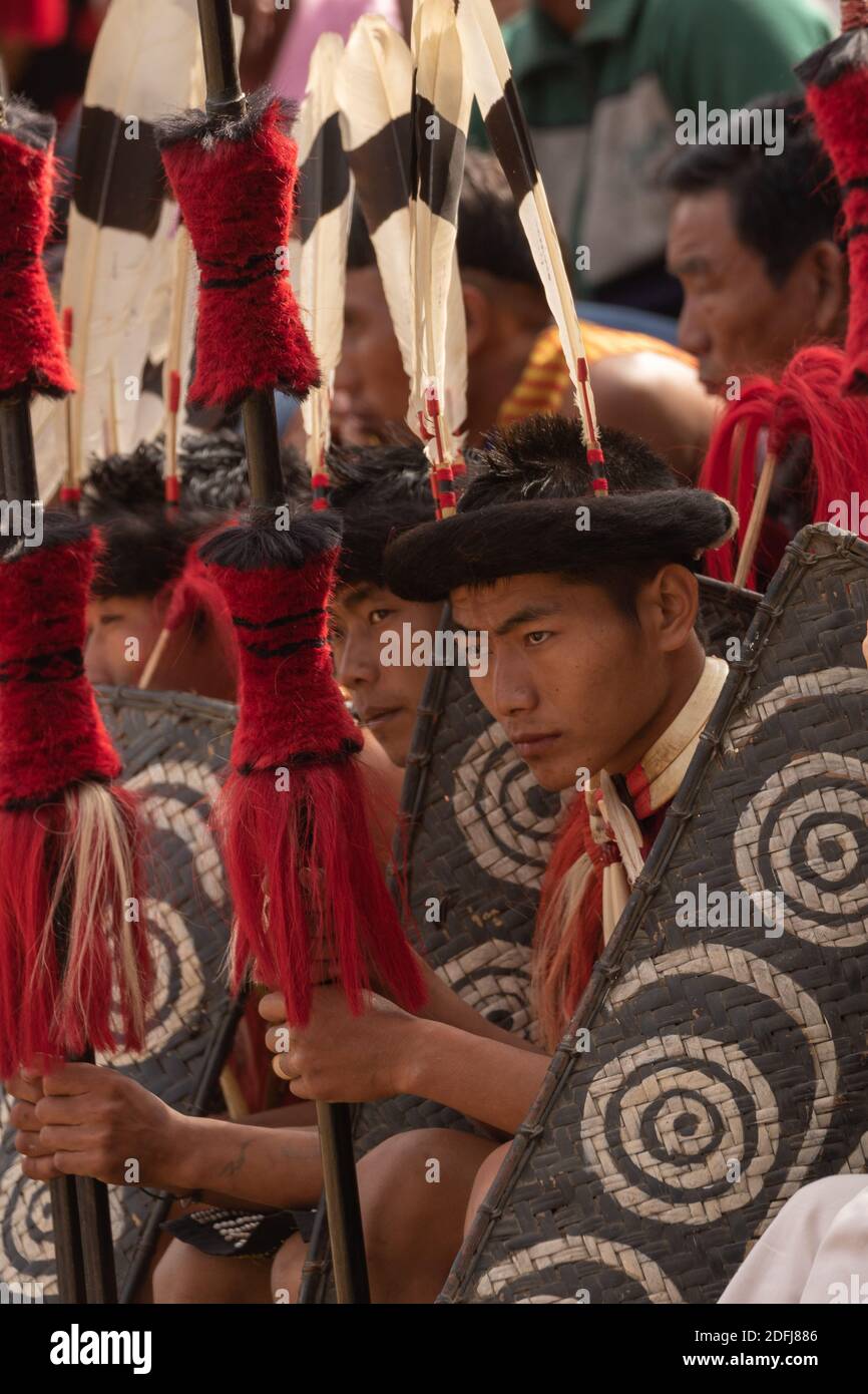 Jeune garçon Naga assis portant une tenue colorée et des engrenages de tête Au village du patrimoine de Kisama, dans le Nagaland Inde, le 3 décembre 2016 Banque D'Images