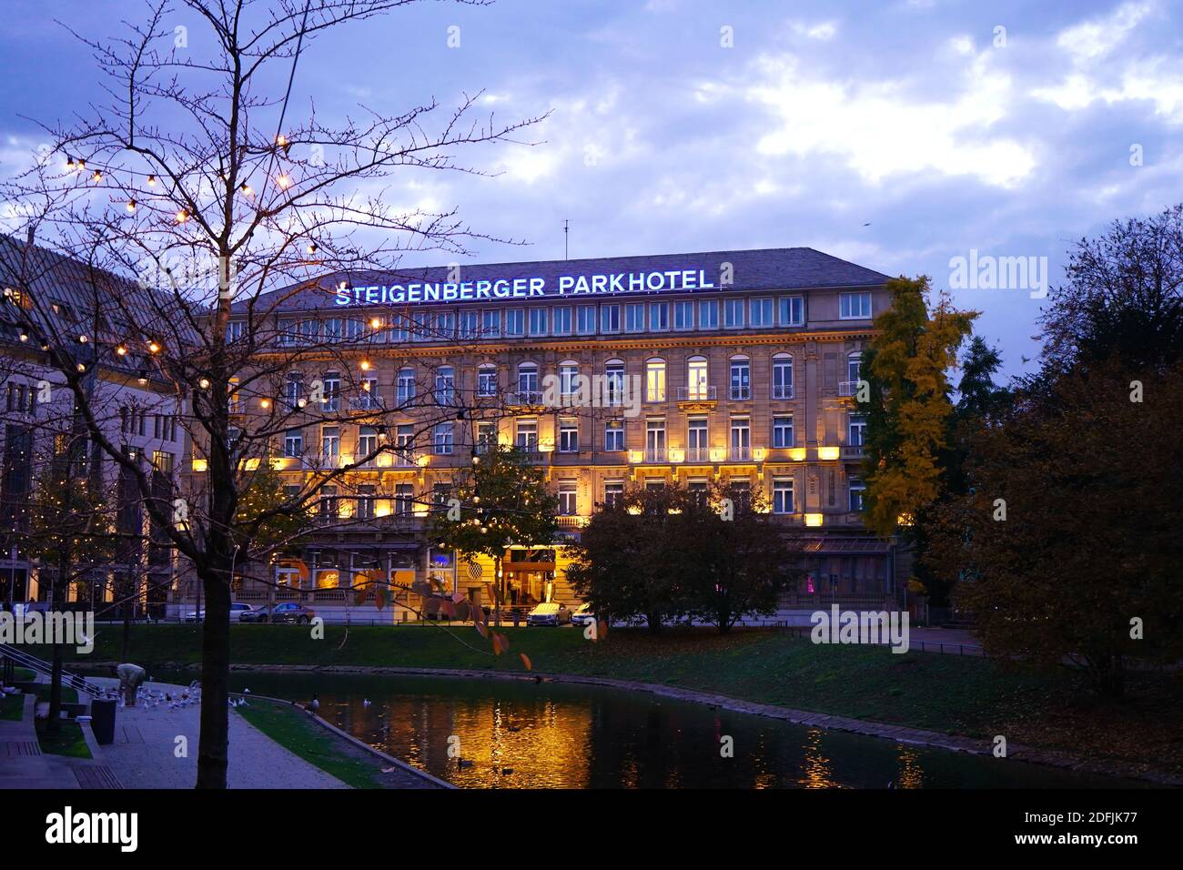 Vue sur l''hôtel lumineux de première classe 'Steigenberger Parkhotel' en soirée avec arbres de Noël en face. Banque D'Images