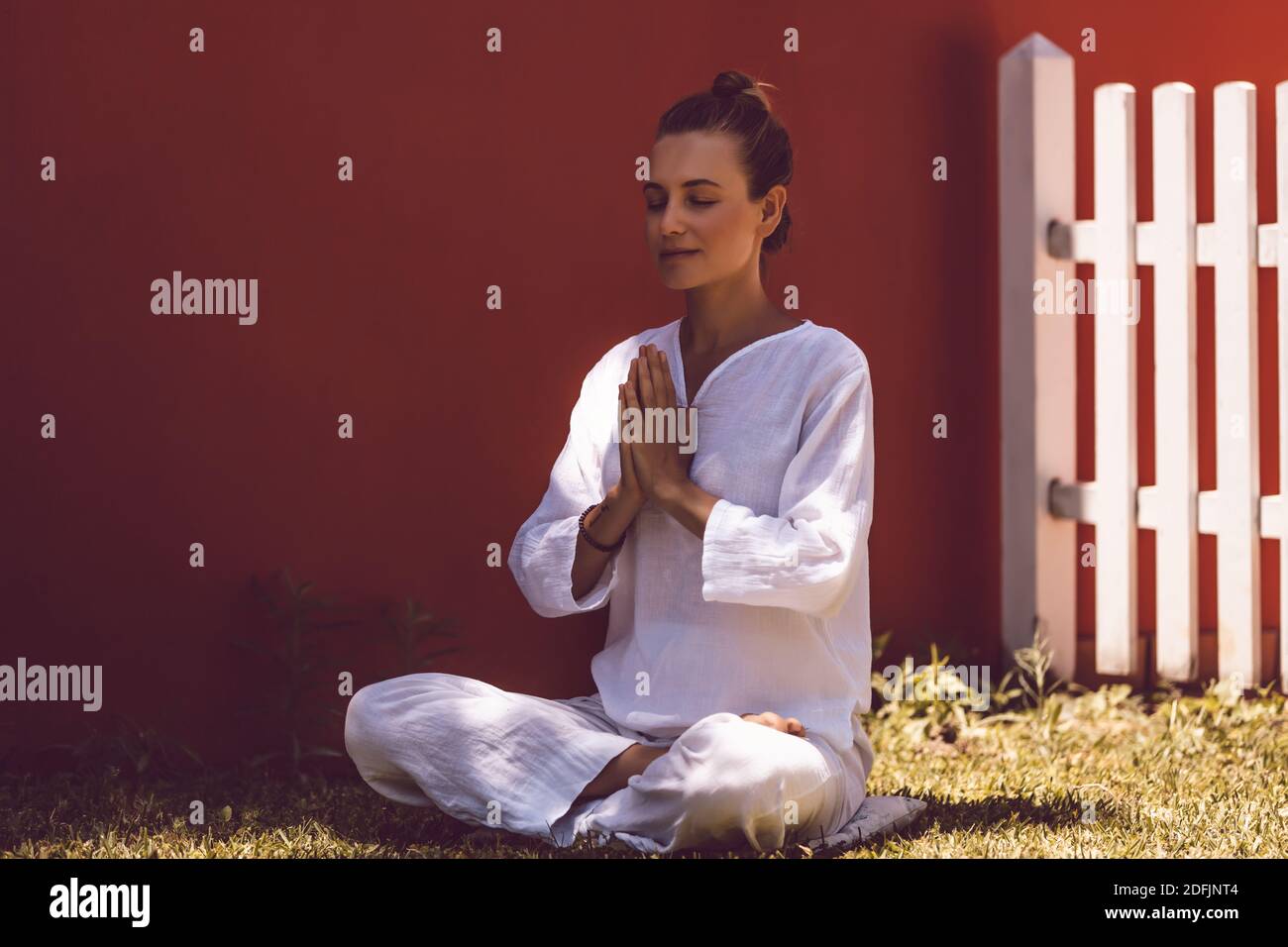 Belle femme paisible faisant des exercices de yoga dans l'arrière-cour. Médite avec les yeux fermés en position Lotus. Un style de vie sain. Corps esprit et âme. Banque D'Images