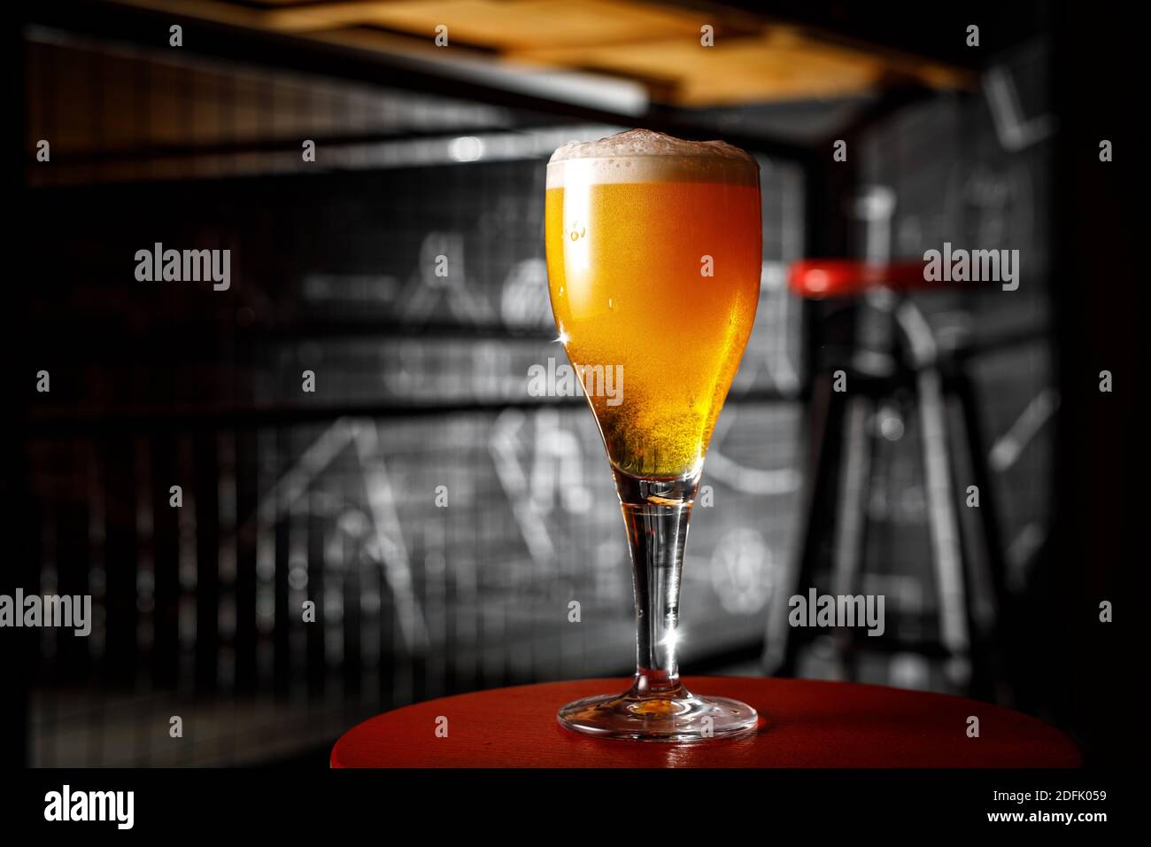 Un verre de bière blonde sur une jambe fine dedans un bar Banque D'Images