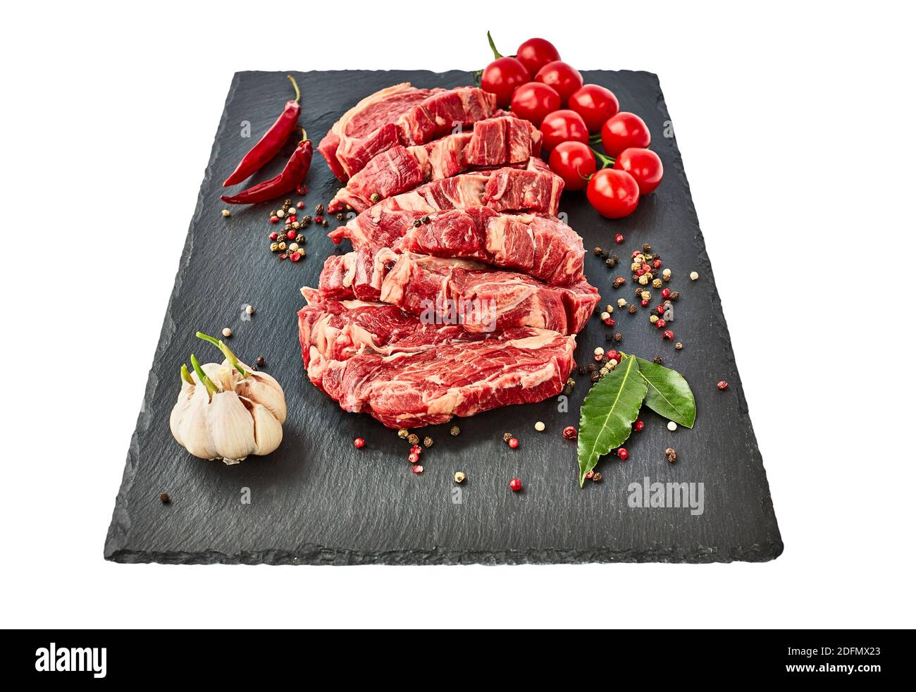 Steaks de bœuf frais crus au poivre et aux tomates sur un panneau d'ardoise noir. Isolé sur fond blanc. Espace de copie, vue de dessus. Banque D'Images