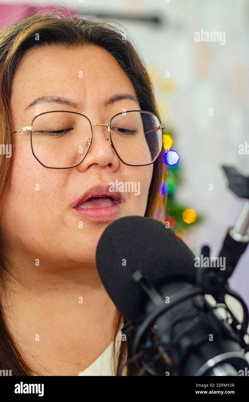 Une dame chantant dans un microphone, enregistrant des voix pour une chanson. Banque D'Images