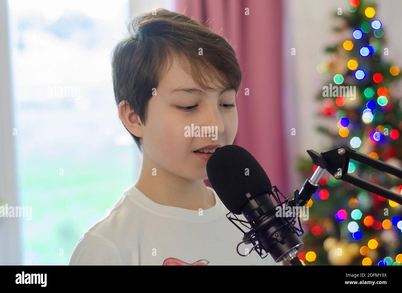 Un garçon chantant dans un microphone, enregistrant des voix pour une chanson. Banque D'Images