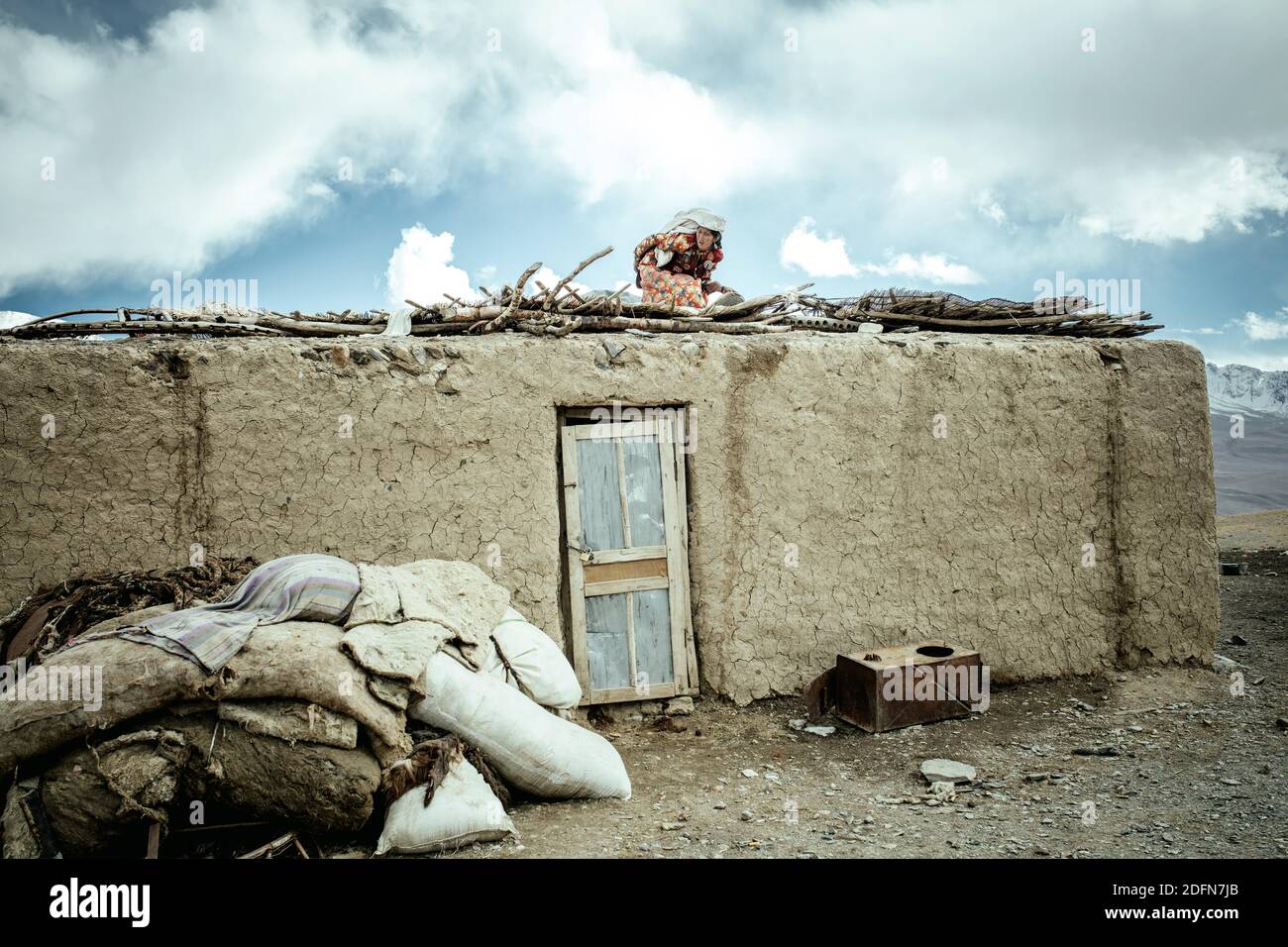 Femme sur le toit d'une maison de boue, en train de sécher des gâteaux plats à la vache, Khadz Goz, couloir de Wakhan, Badakhshan, Afghanistan Banque D'Images