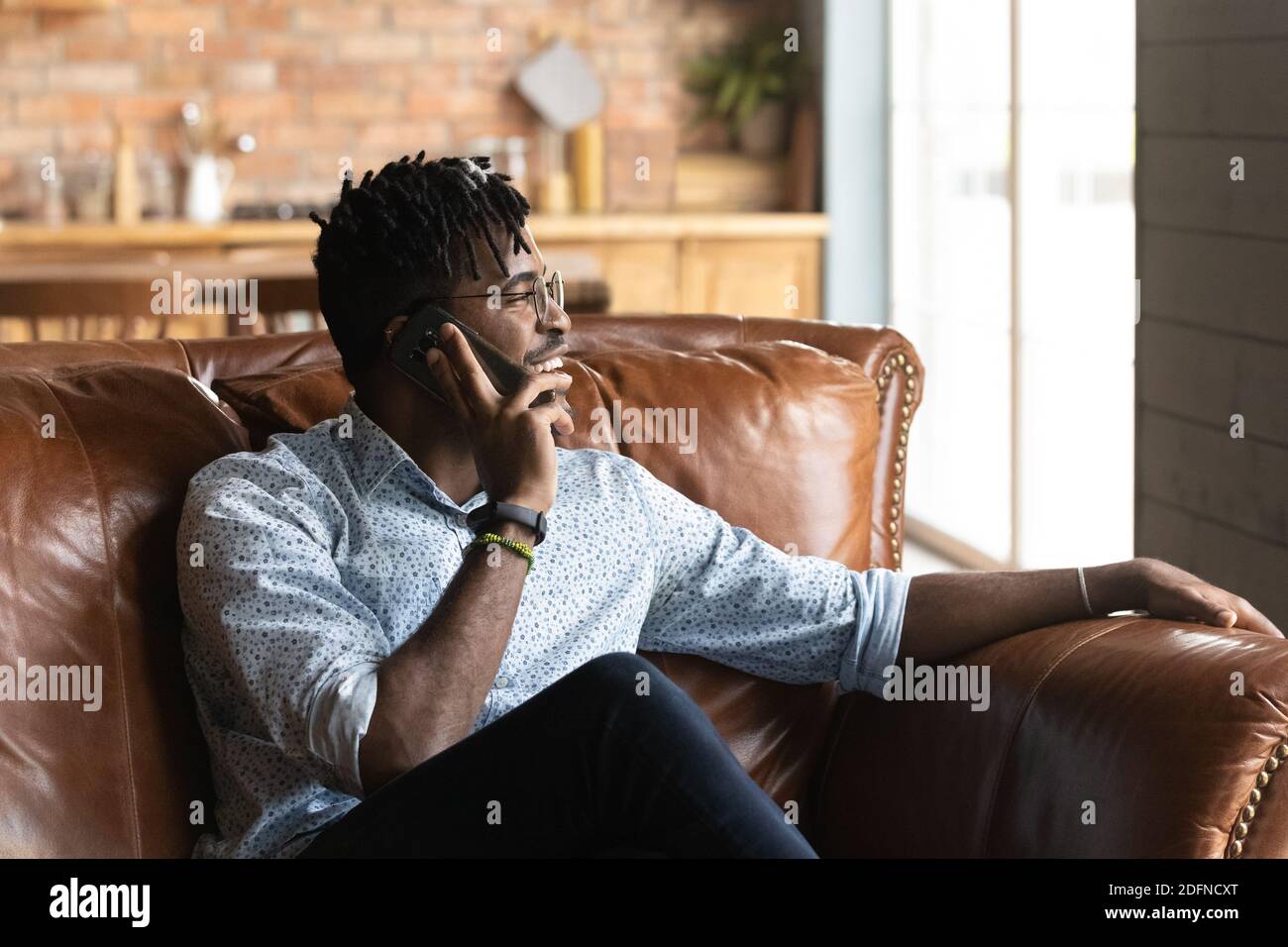 Joyeux jeune homme africain de race mixte parlant sur le téléphone portable. Banque D'Images