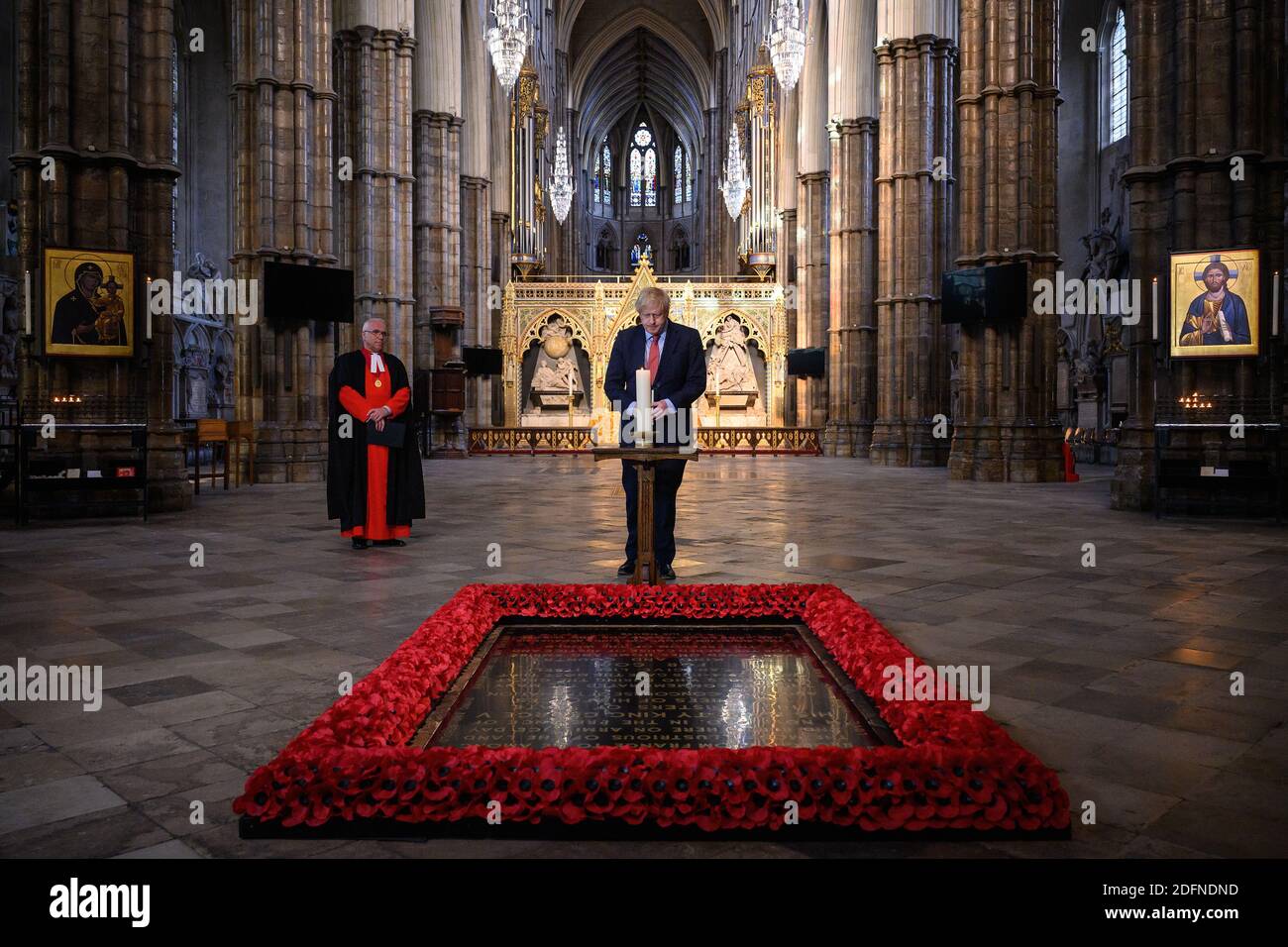 Photo du dossier datée du 07/05/20 du doyen de Westminster, le révérend Dr David Hoyle (à gauche), regardant comme le Premier ministre Boris Johnson allume une bougie à la tombe du guerrier inconnu à l'abbaye de Westminster à Londres, en prévision des commémorations pour marquer le 75e anniversaire de la Ve journée. Le 13 décembre 2020 marque le premier anniversaire de la victoire aux élections générales de M. Johnson. Banque D'Images