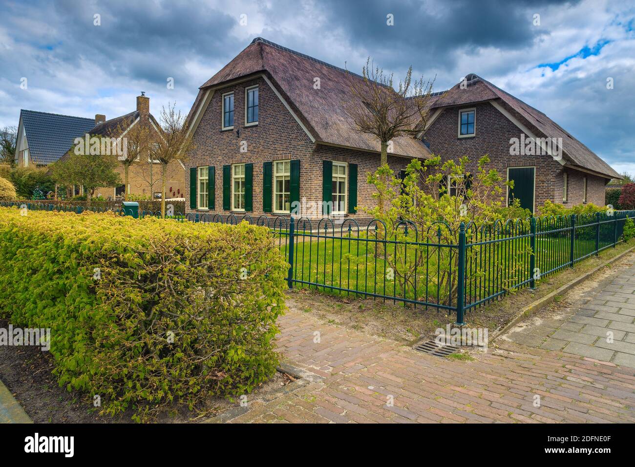 Magnifique maison hollandaise de luxe avec toit de chaume et cour avant ordonnée. Jardin spectaculaire avec herbe verte et plantes. Façade avec jardin et vert b Banque D'Images