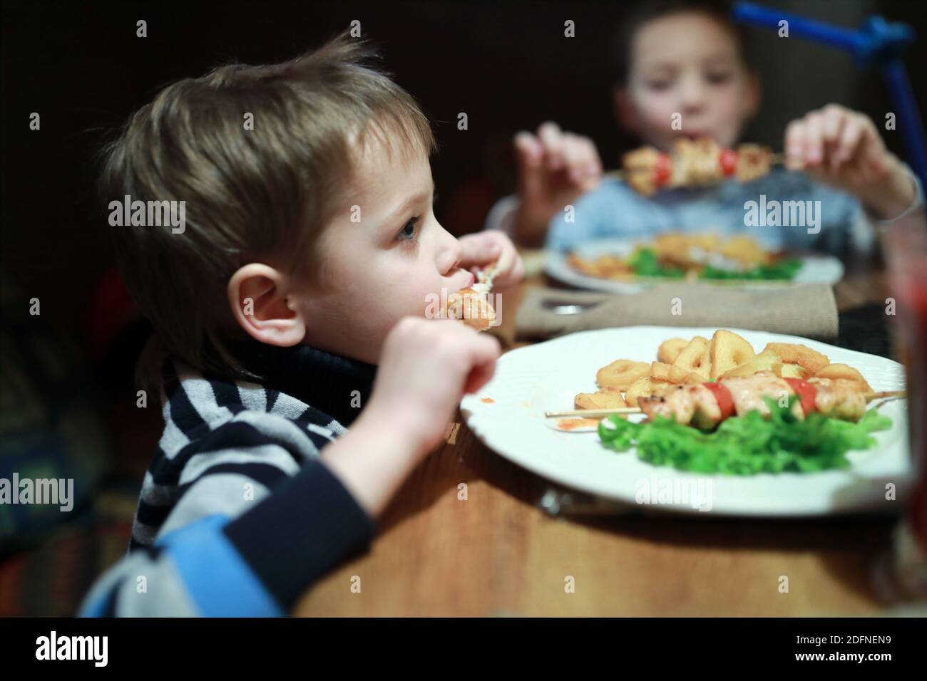 Les enfants mangent du kebab sur des brochettes dans le restaurant Banque D'Images