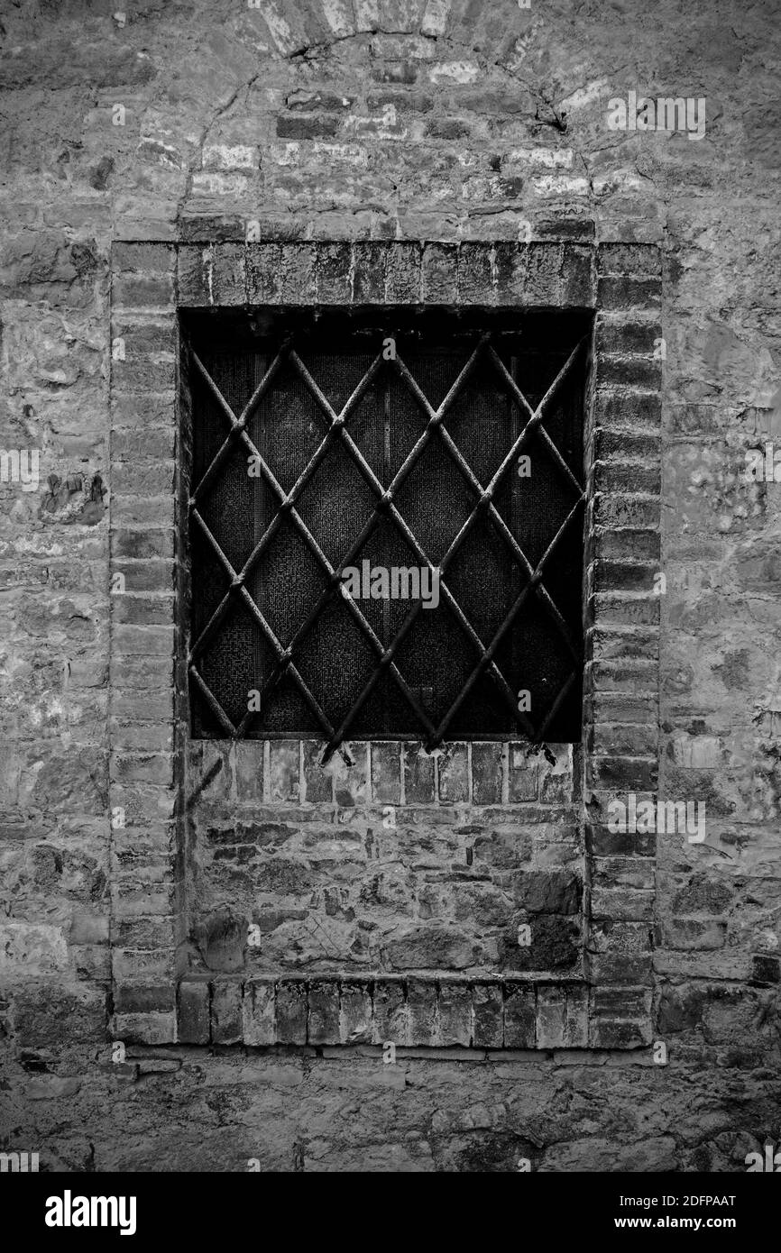 Une fenêtre partiellement vibrifiée dans le village médiéval historique de San Quirico d'Orcia, province de Sienne, Toscane, Italie Banque D'Images