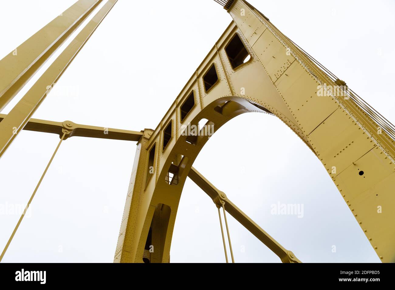 Vue extrême vers le haut d'un pont de suspension auto-ancré peint en jaune vif contre un ciel couvert, aspect horizontal Banque D'Images